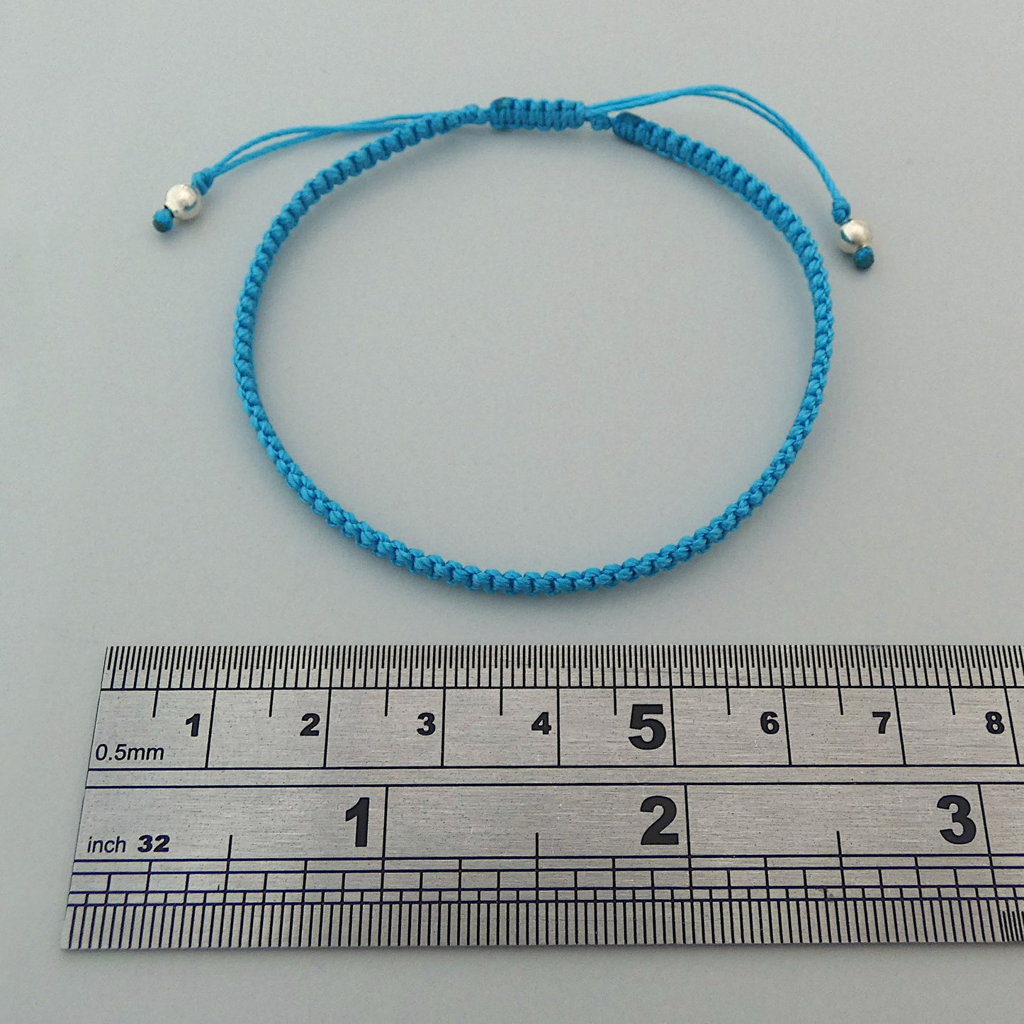 7” adjustable Bermuda blue macramé bracelet for adults with silver plated bead ends.