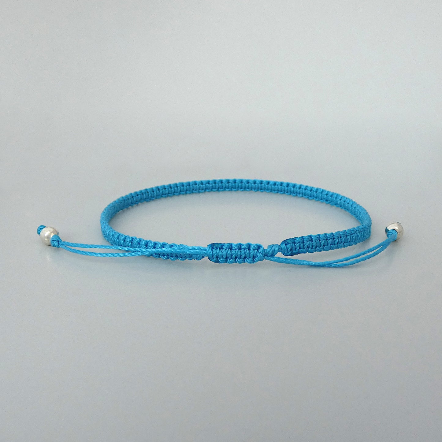 7” adjustable Bermuda blue macramé bracelet for adults with silver plated bead ends.