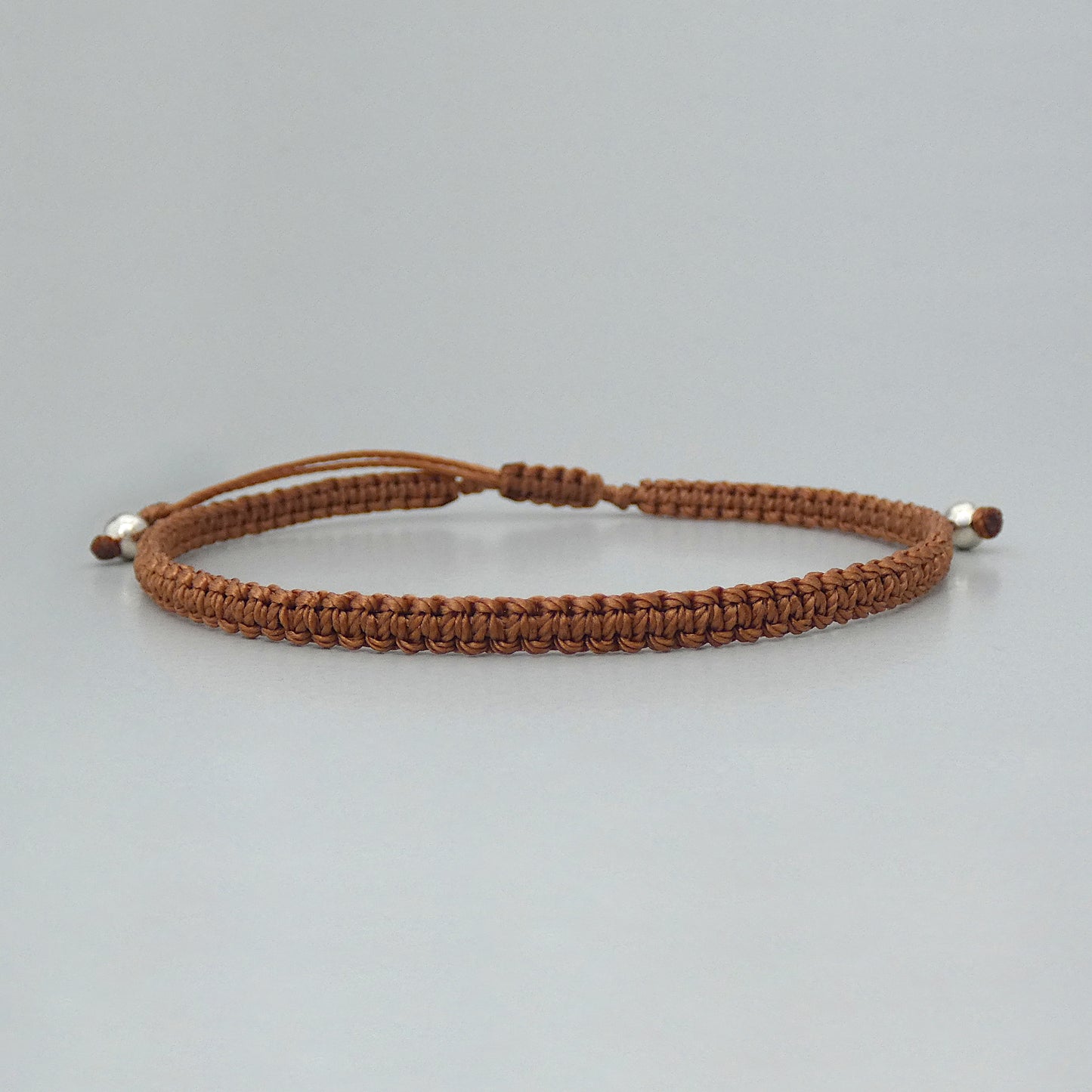 7” adjustable copper coloured macramé bracelet for adults with silver plated bead ends.