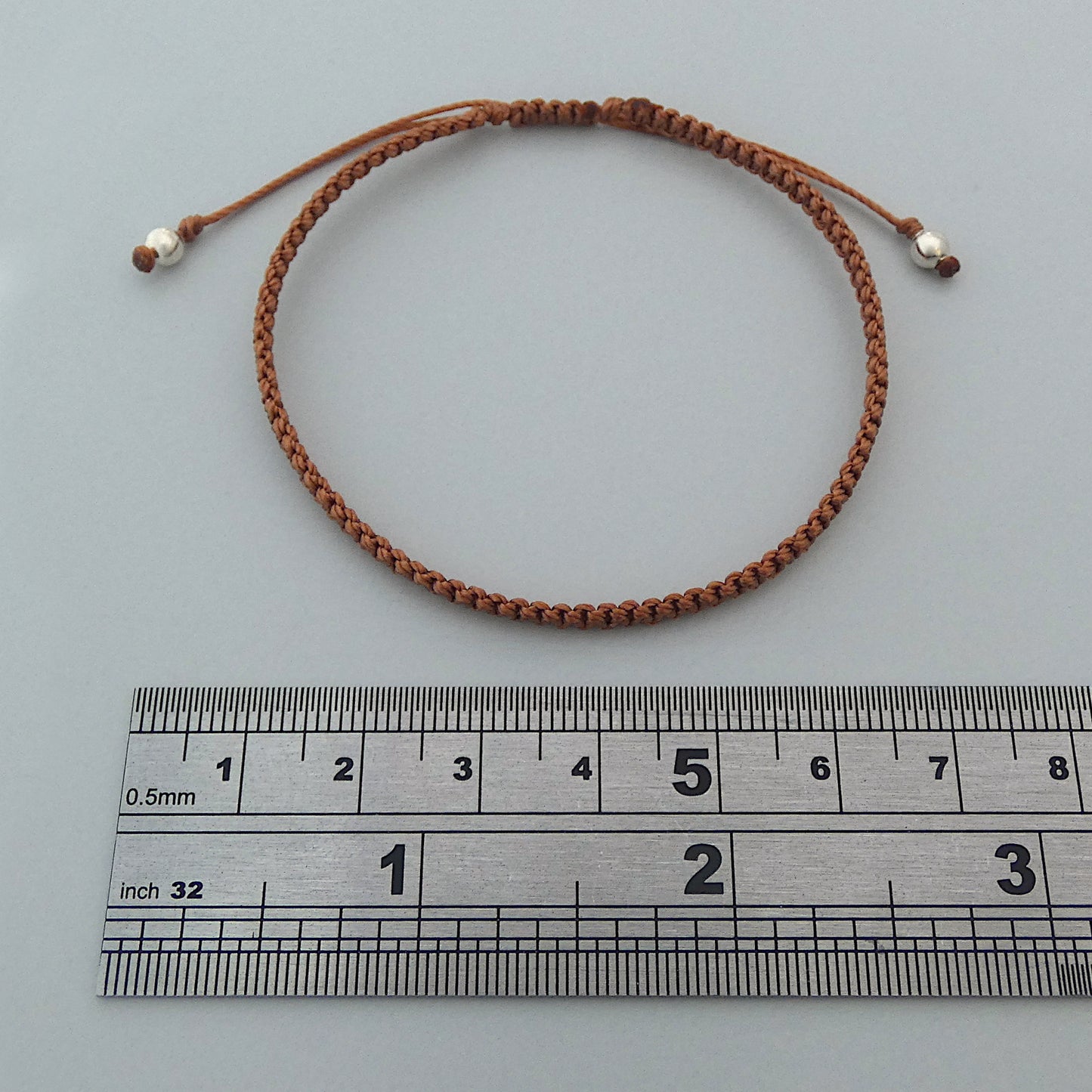 7” adjustable copper coloured macramé bracelet for adults with silver plated bead ends.
