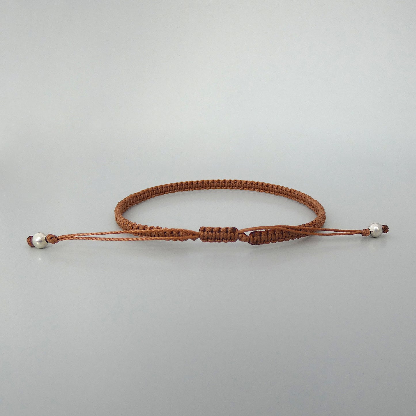 7” adjustable copper coloured macramé bracelet for adults with silver plated bead ends.