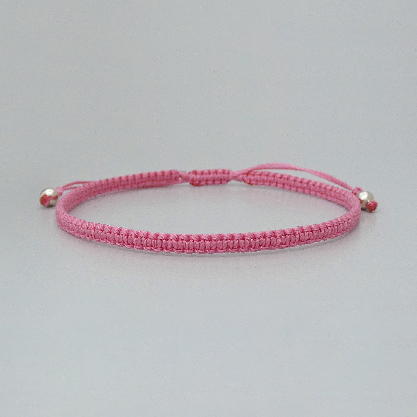 7” adjustable pink coloured macramé bracelet for adults with silver plated bead ends.