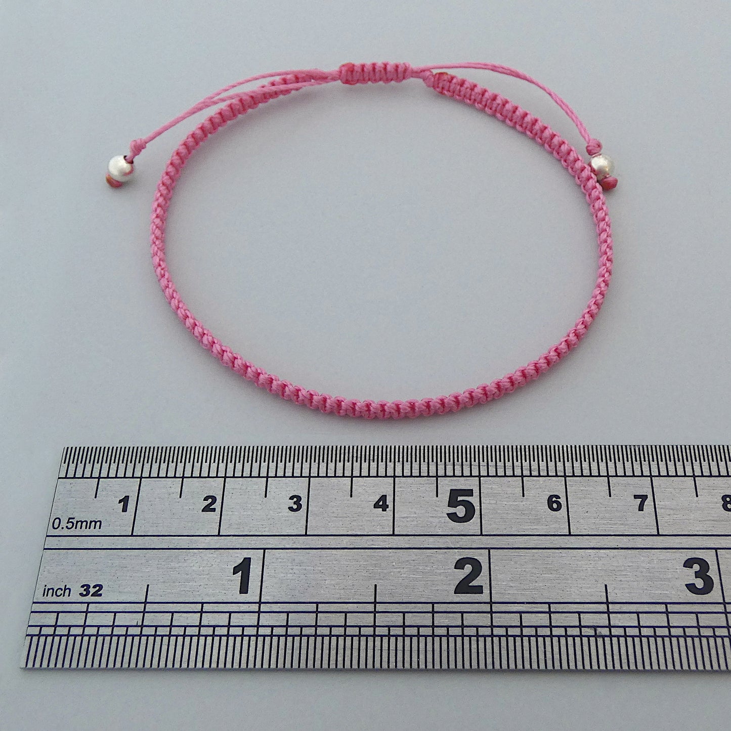 7” adjustable pink coloured macramé bracelet for adults with silver plated bead ends.