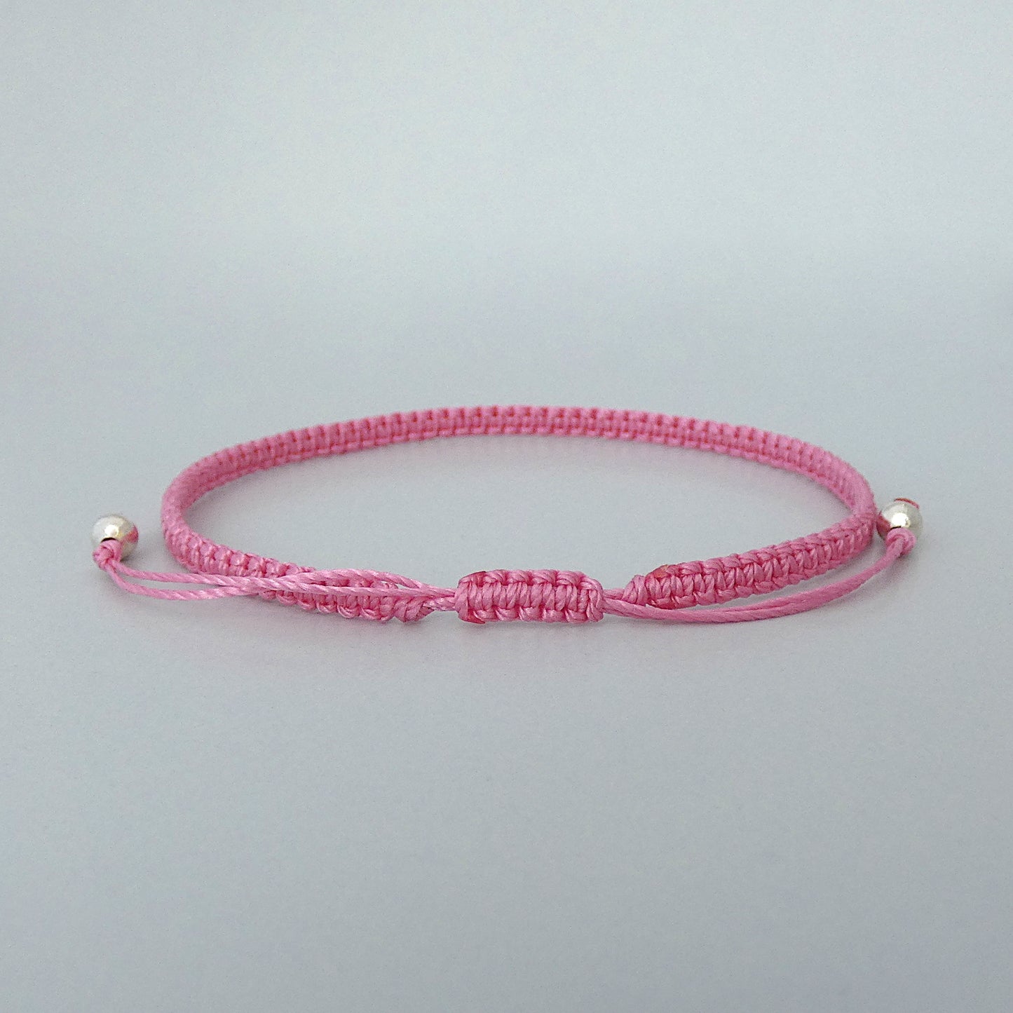 7” adjustable pink coloured macramé bracelet for adults with silver plated bead ends.