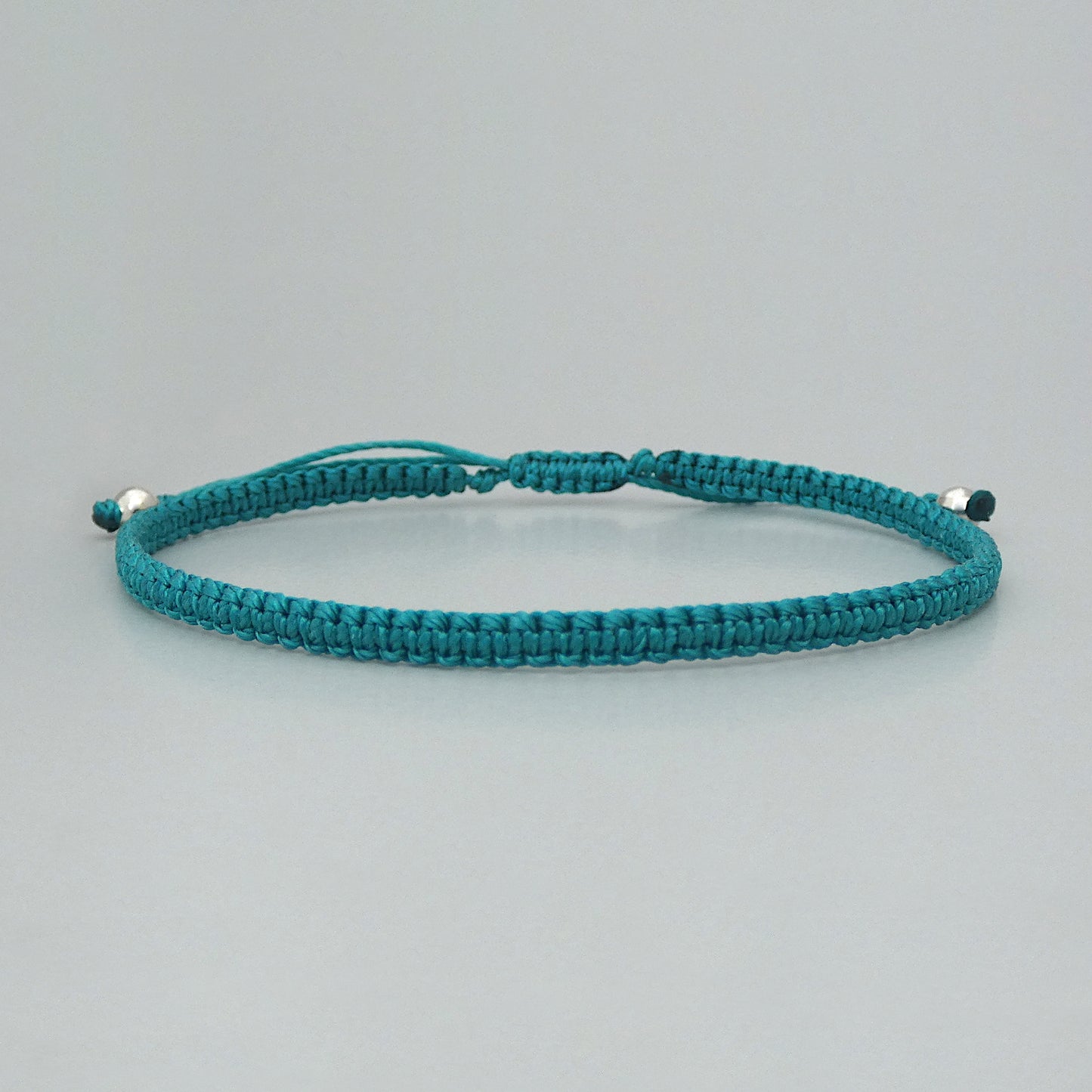 7” adjustable teal coloured macramé bracelet for adults with silver plated bead ends.