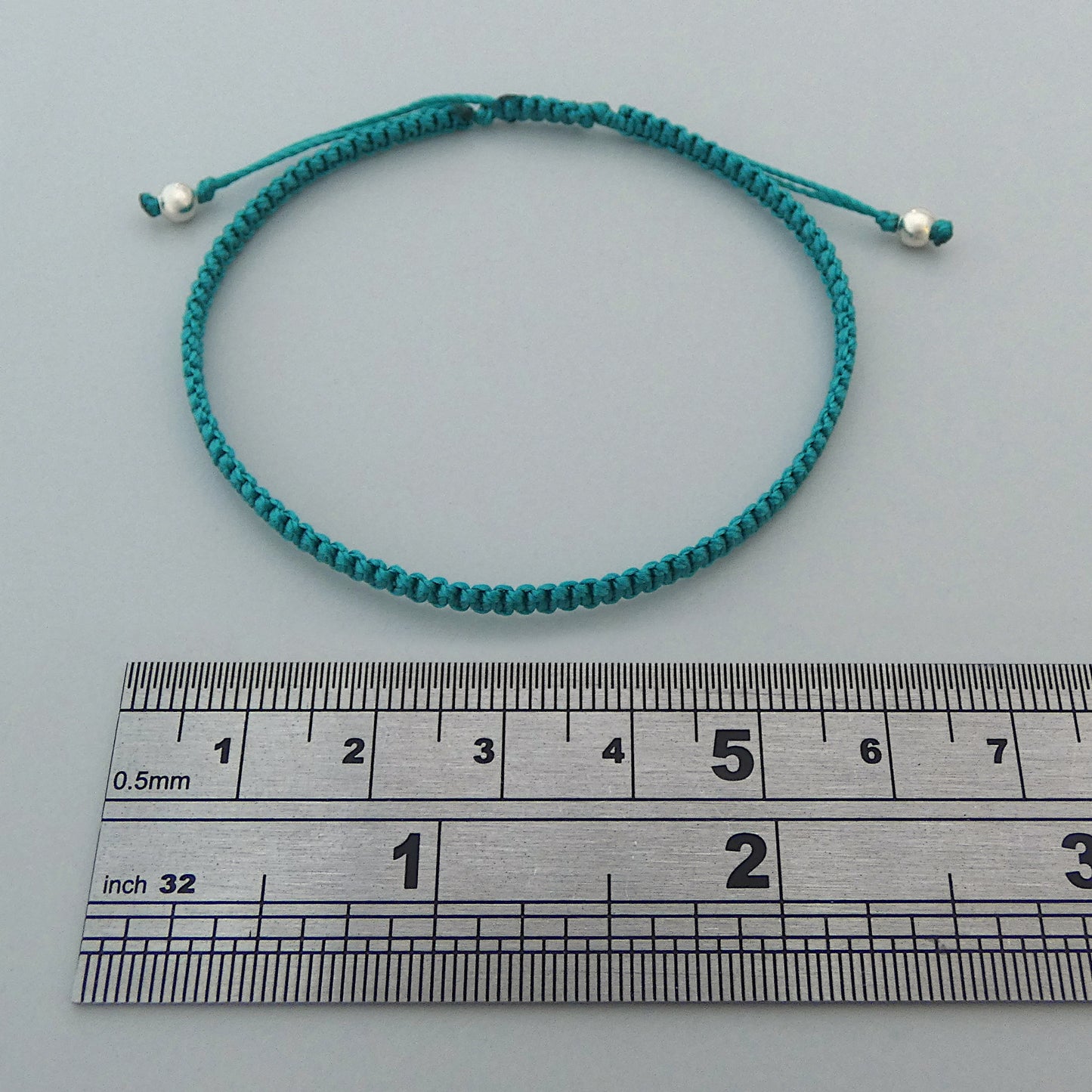 7” adjustable teal coloured macramé bracelet for adults with silver plated bead ends.