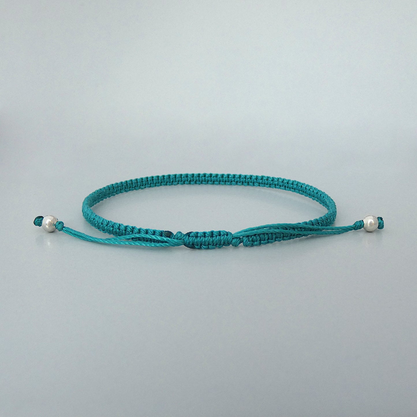 7” adjustable teal coloured macramé bracelet for adults with silver plated bead ends.