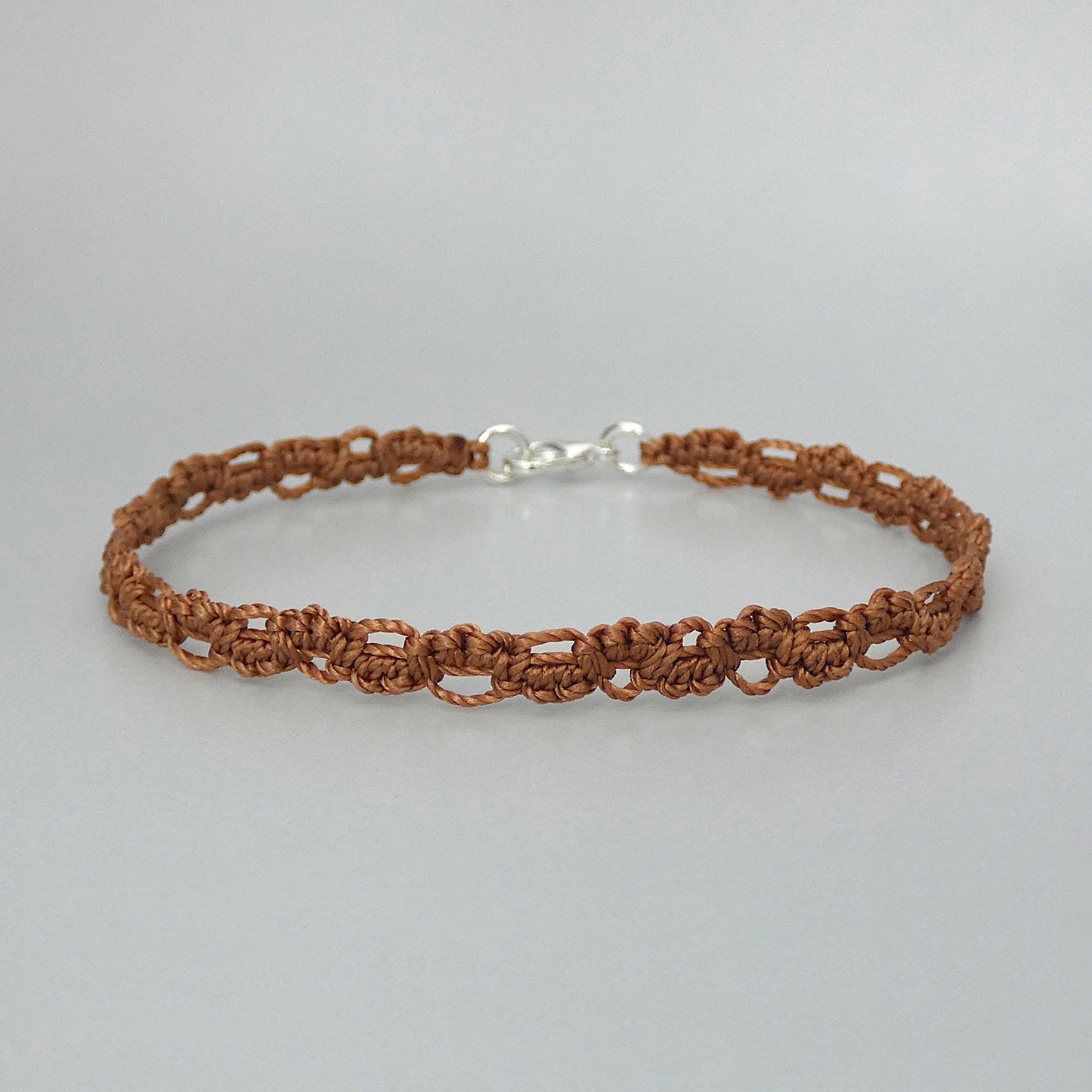 Copper coloured macramé bracelet tied with an intricate lace effect with silver plated clasp and optional 1” extender chain.