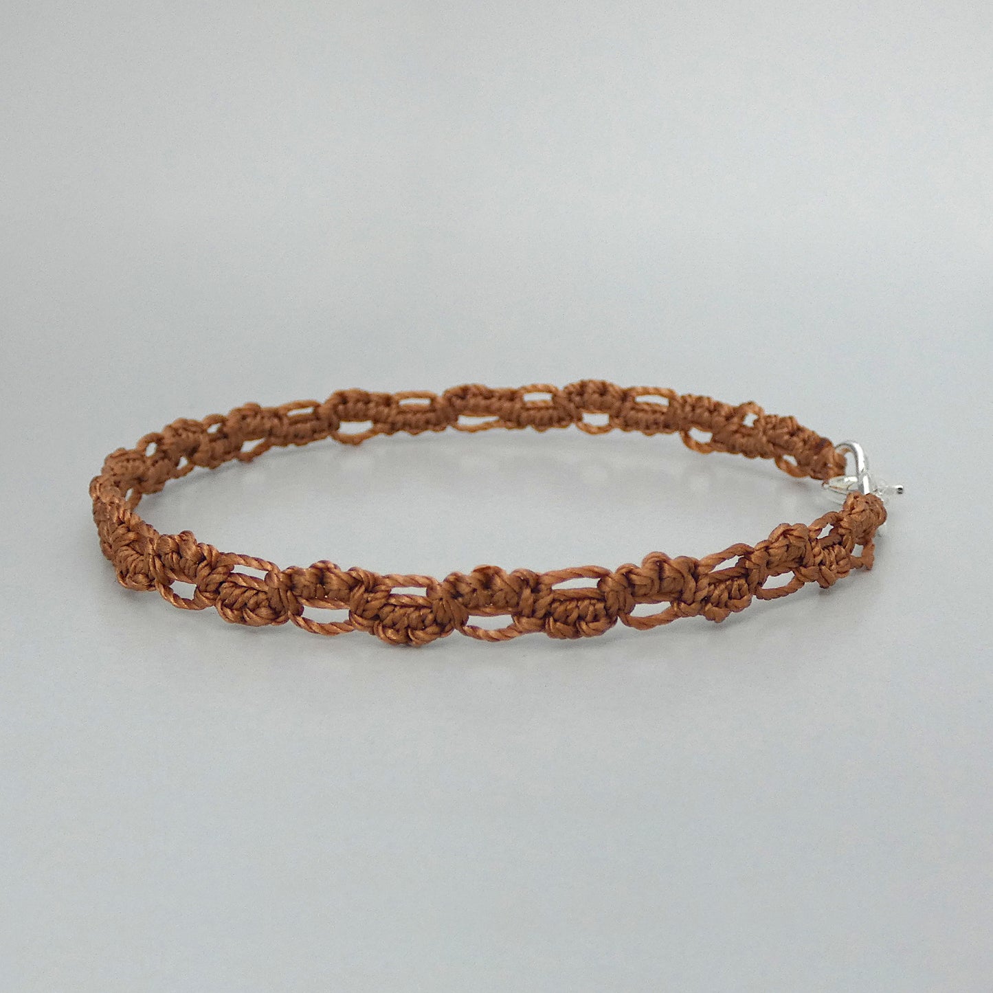 Copper coloured macramé bracelet tied with an intricate lace effect with silver plated clasp and optional 1” extender chain.