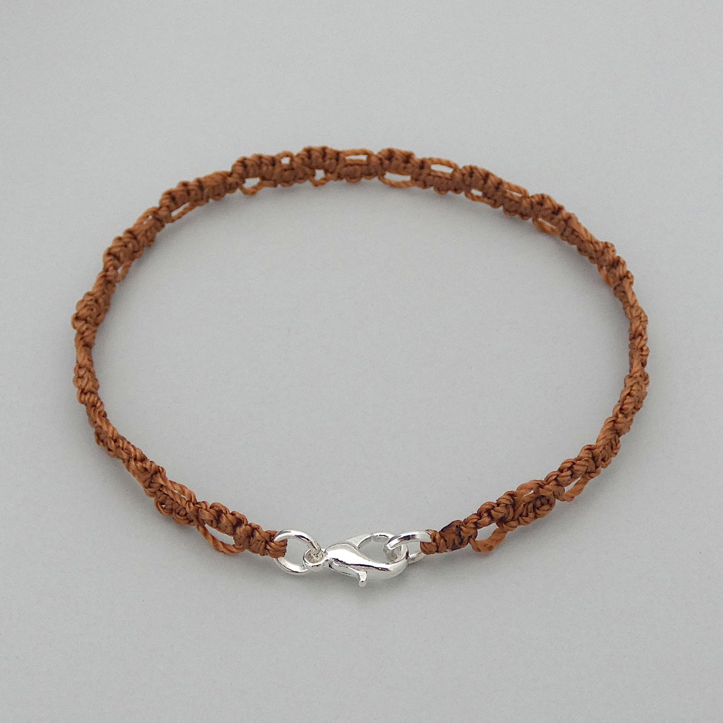 Copper coloured macramé bracelet tied with an intricate lace effect with silver plated clasp and optional 1” extender chain.