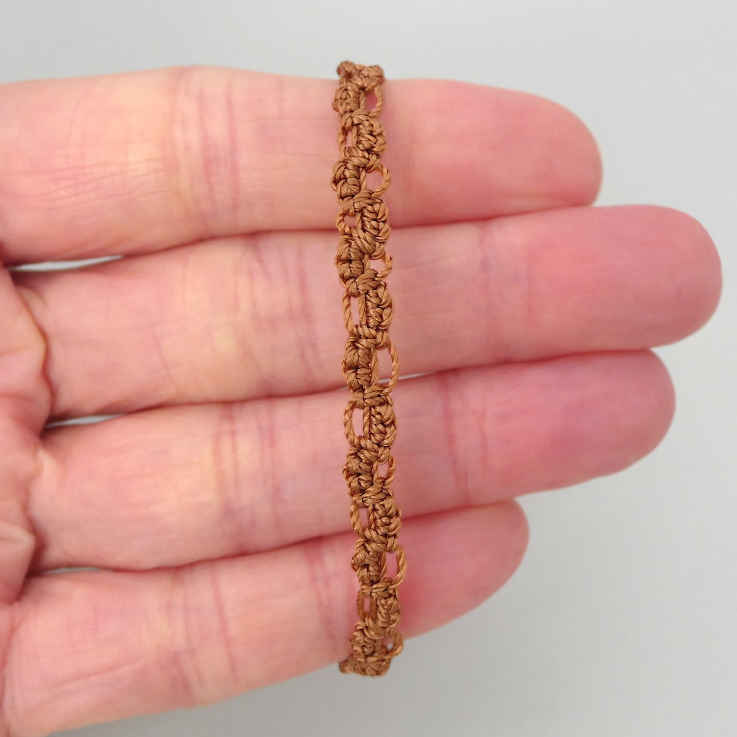 Copper coloured macramé bracelet tied with an intricate lace effect with silver plated clasp and optional 1” extender chain.