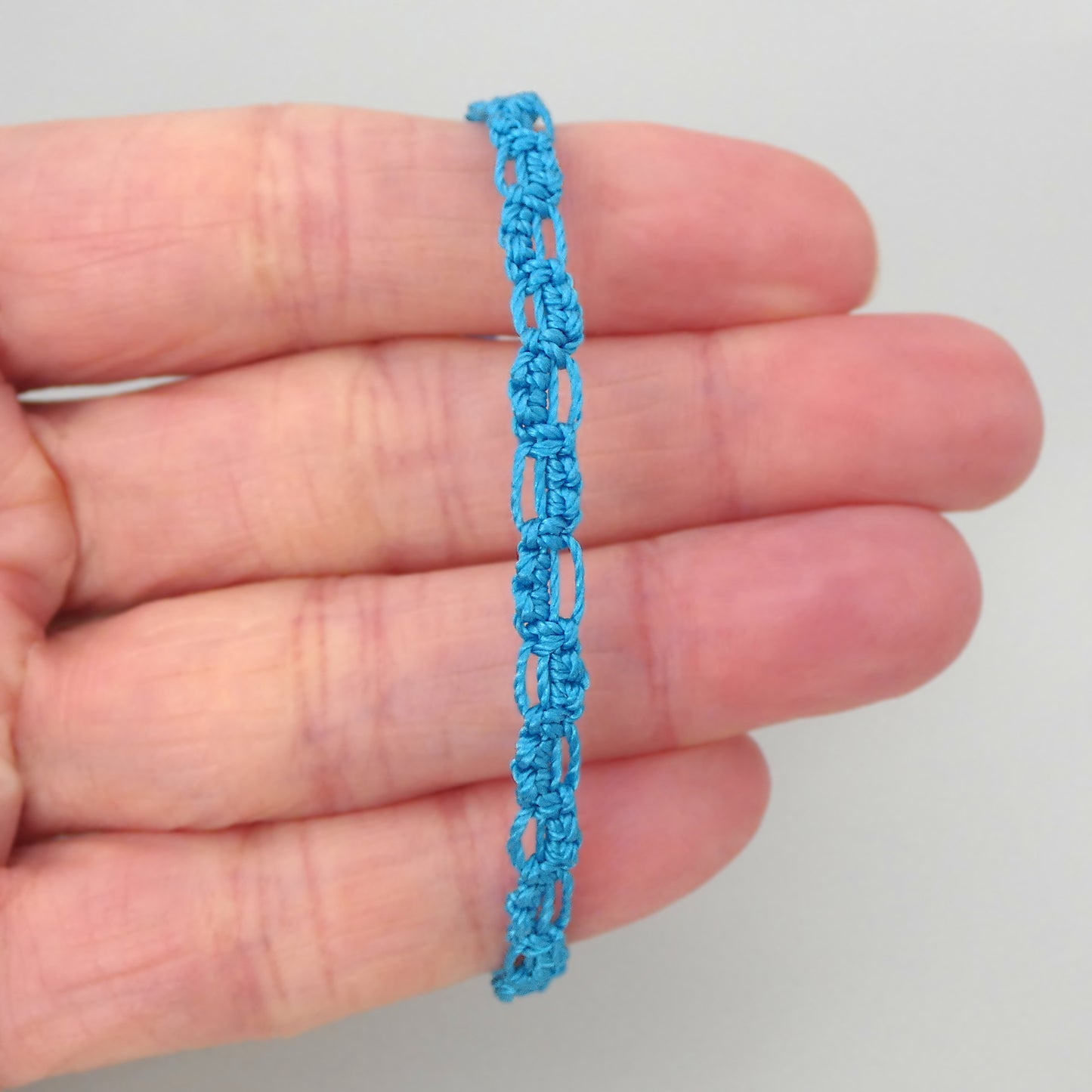 Bermuda blue macramé bracelet tied with an intricate lace effect with silver plated clasp and optional 1” extender chain.