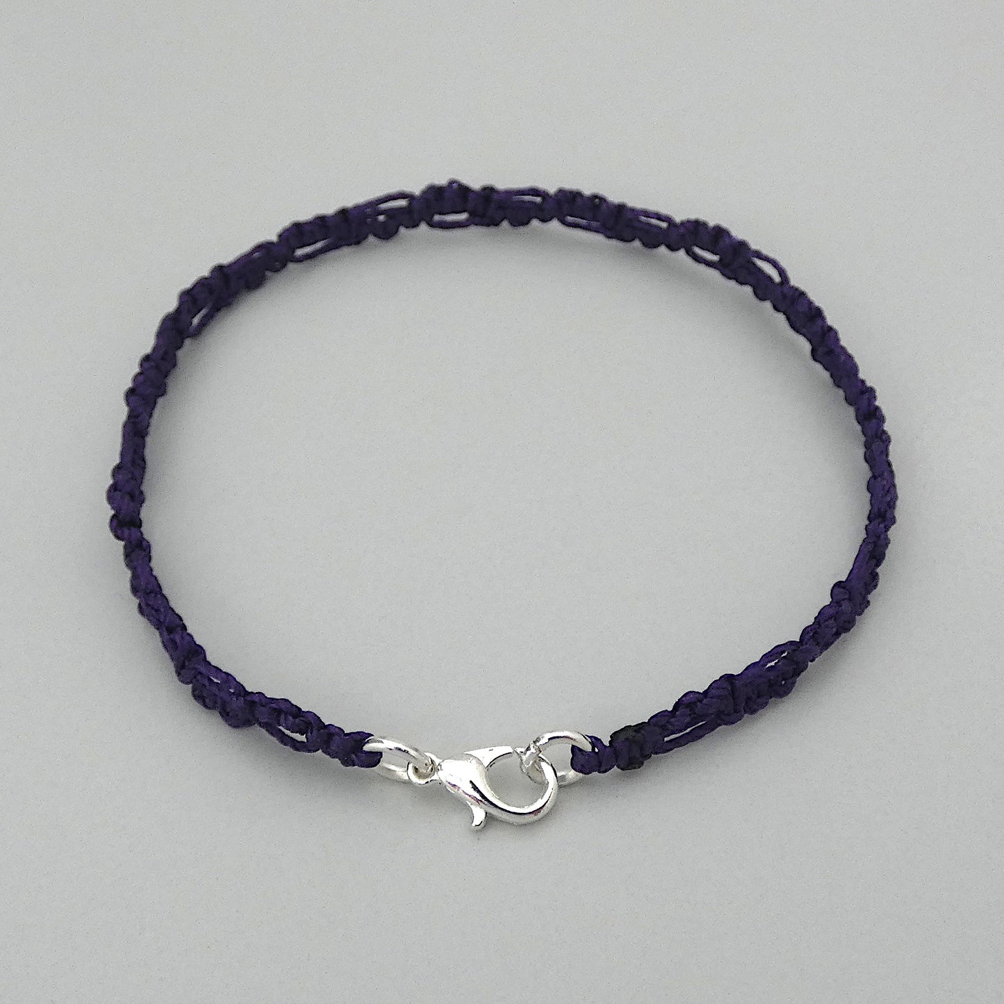 Dark purple macramé bracelet tied with an intricate lace effect with silver plated clasp and optional 1” extender chain.