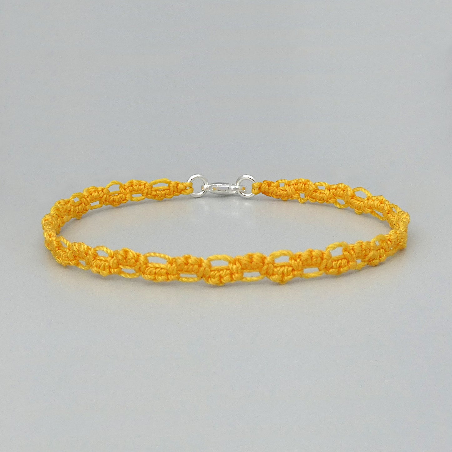 Golden yellow macramé bracelet tied with an intricate lace effect with silver plated clasp and optional 1” extender chain.