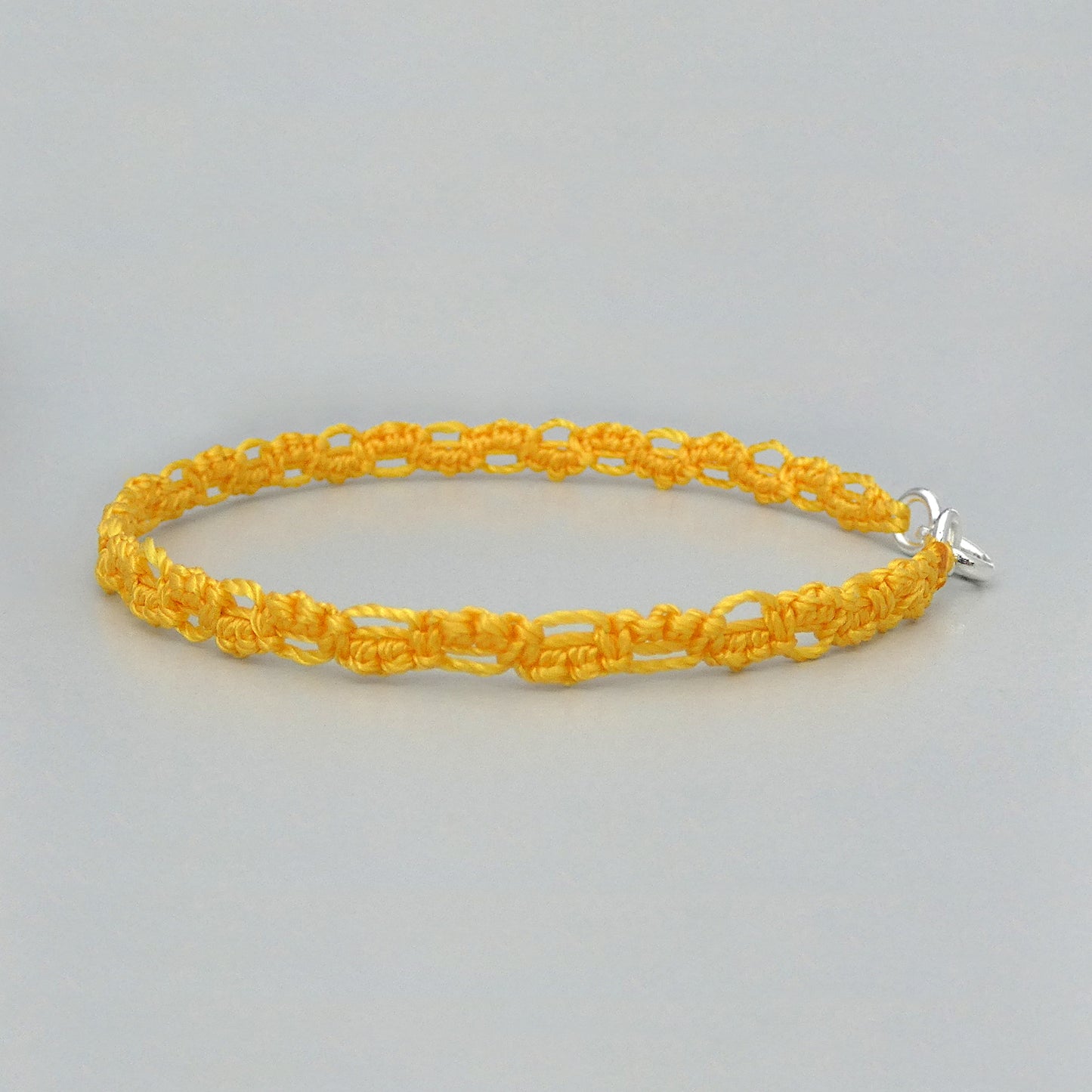 Golden yellow macramé bracelet tied with an intricate lace effect with silver plated clasp and optional 1” extender chain.