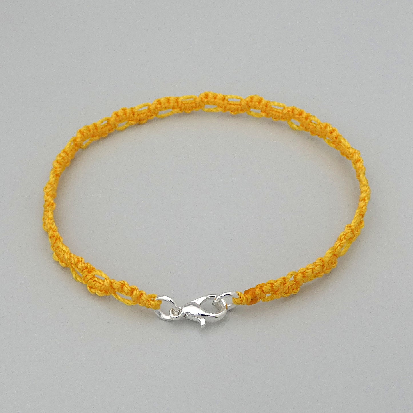 Golden yellow macramé bracelet tied with an intricate lace effect with silver plated clasp and optional 1” extender chain.