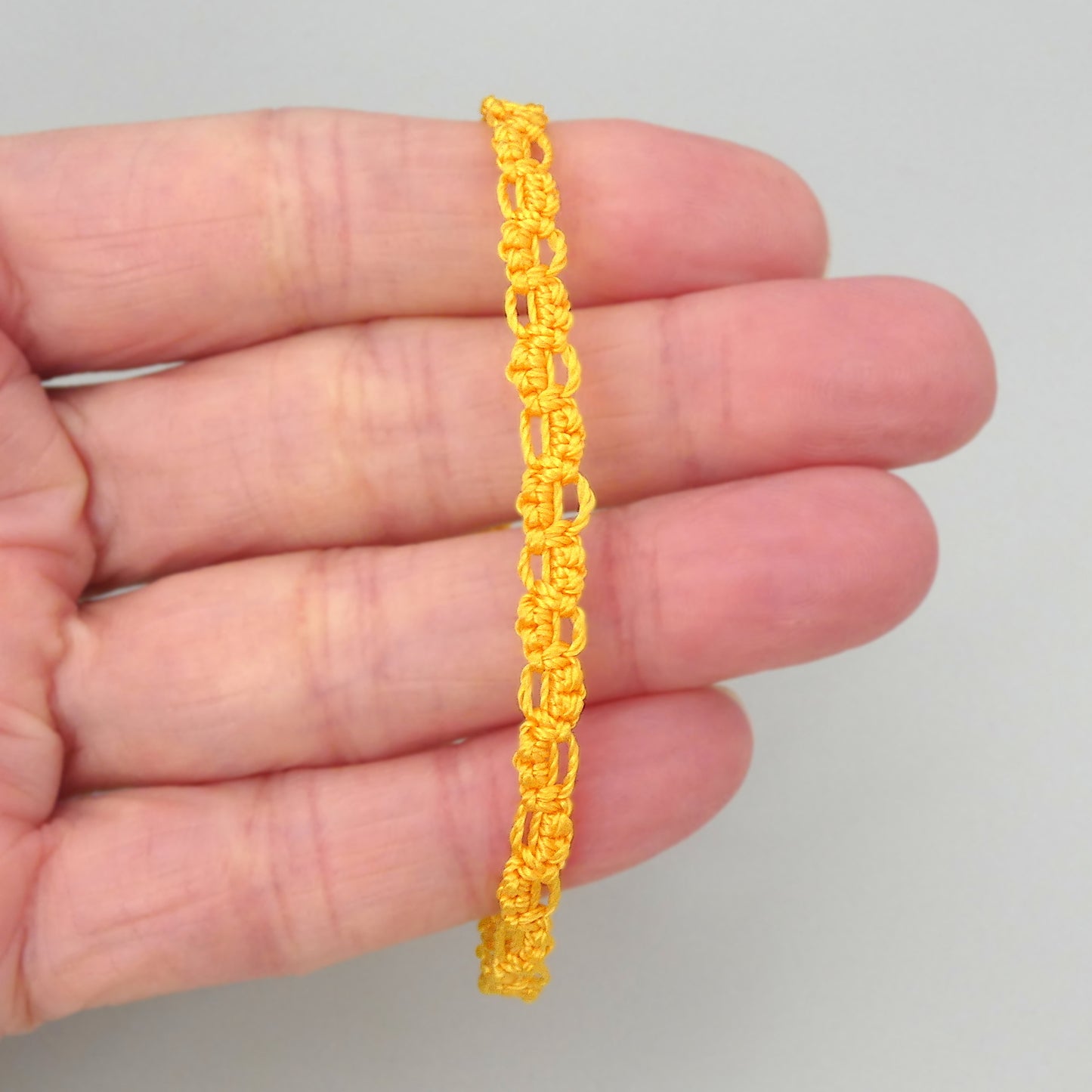 Golden yellow macramé bracelet tied with an intricate lace effect with silver plated clasp and optional 1” extender chain.