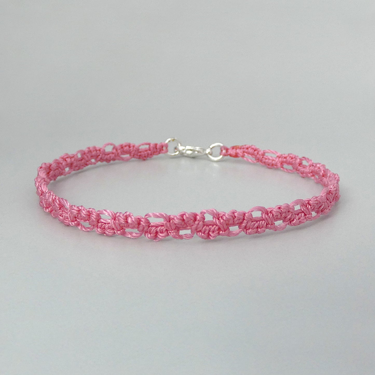 Pink macramé bracelet tied with an intricate lace effect with silver plated clasp and optional 1” extender chain.