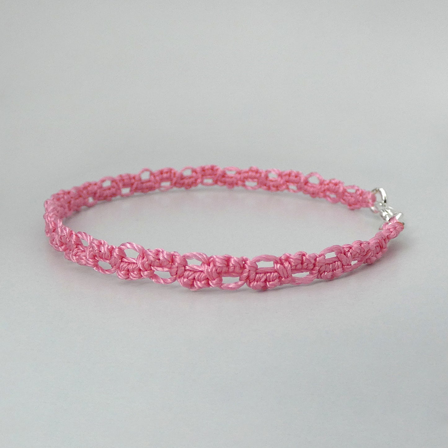 Pink macramé bracelet tied with an intricate lace effect with silver plated clasp and optional 1” extender chain.