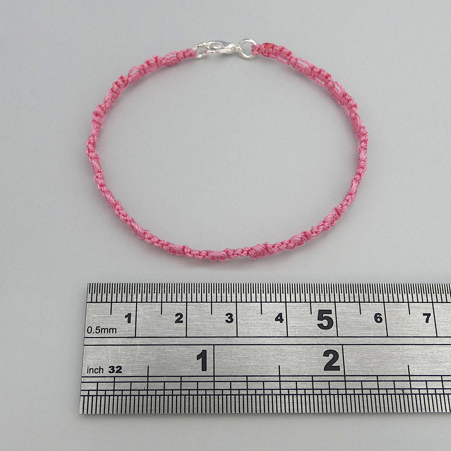Pink macramé bracelet tied with an intricate lace effect with silver plated clasp and optional 1” extender chain.