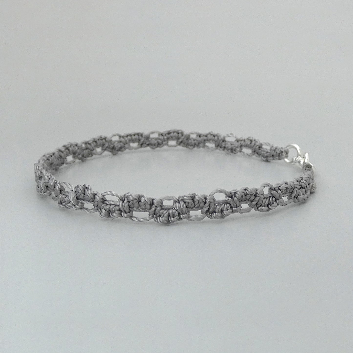 Silver grey macramé bracelet tied with an intricate lace effect with silver plated clasp and optional 1” extender chain.