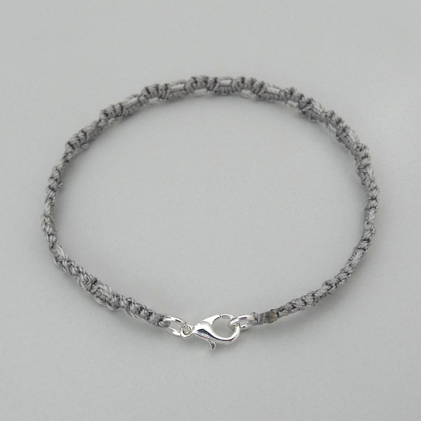 Silver grey macramé bracelet tied with an intricate lace effect with silver plated clasp and optional 1” extender chain.