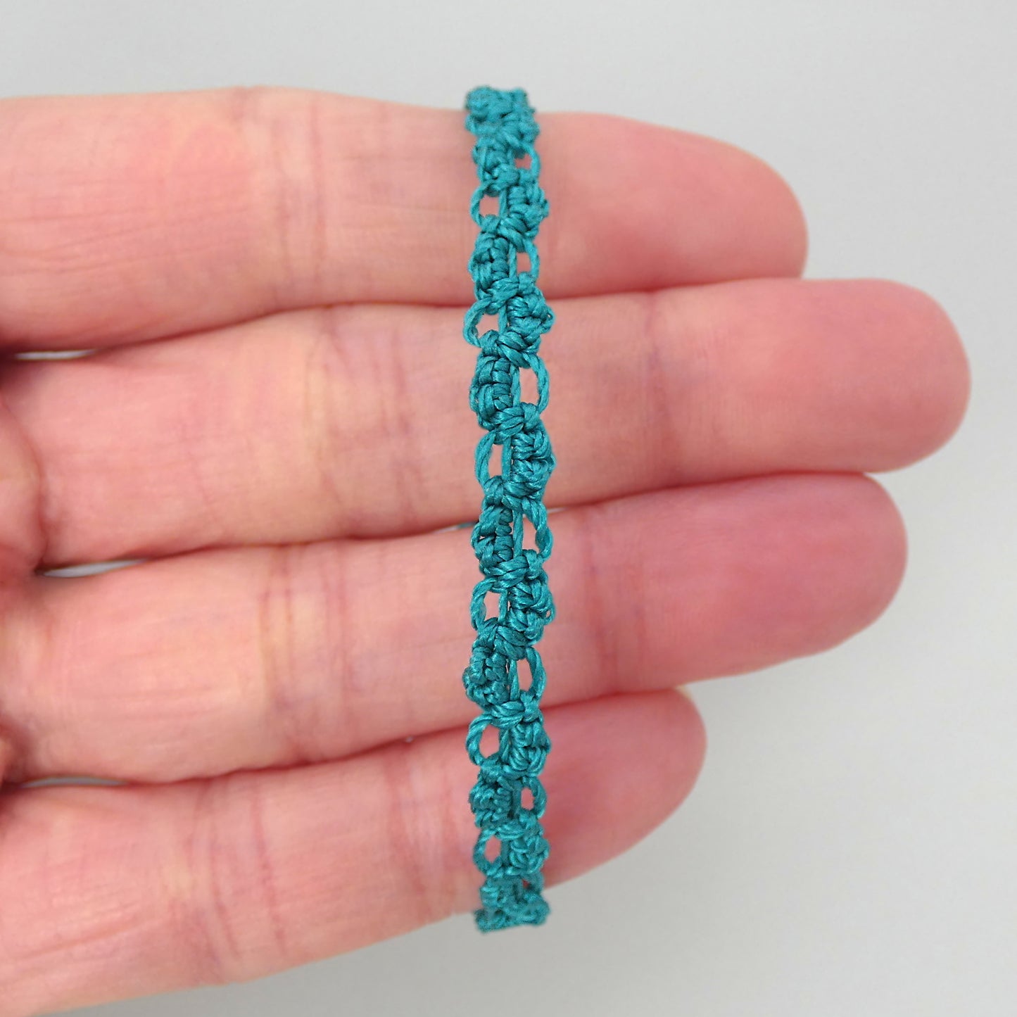 Teal green macramé bracelet tied with an intricate lace effect with silver plated clasp and optional 1” extender chain.
