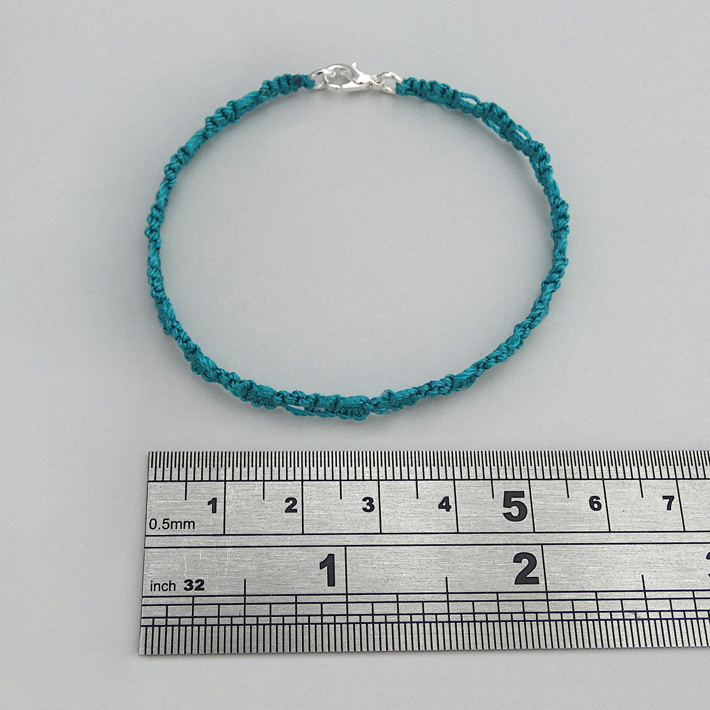 Teal green macramé bracelet tied with an intricate lace effect with silver plated clasp and optional 1” extender chain.