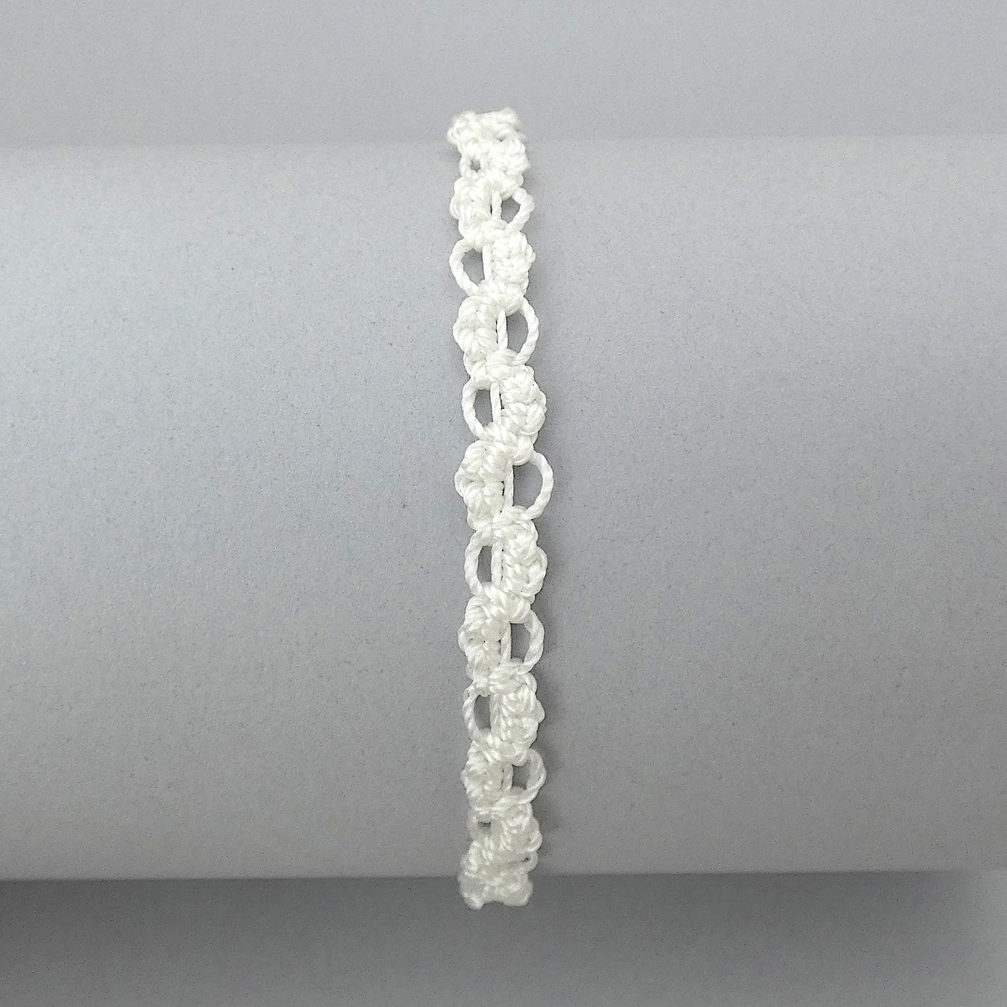 White macramé bracelet tied with an intricate wave effect with silver plated clasp and optional 1” extender chain.