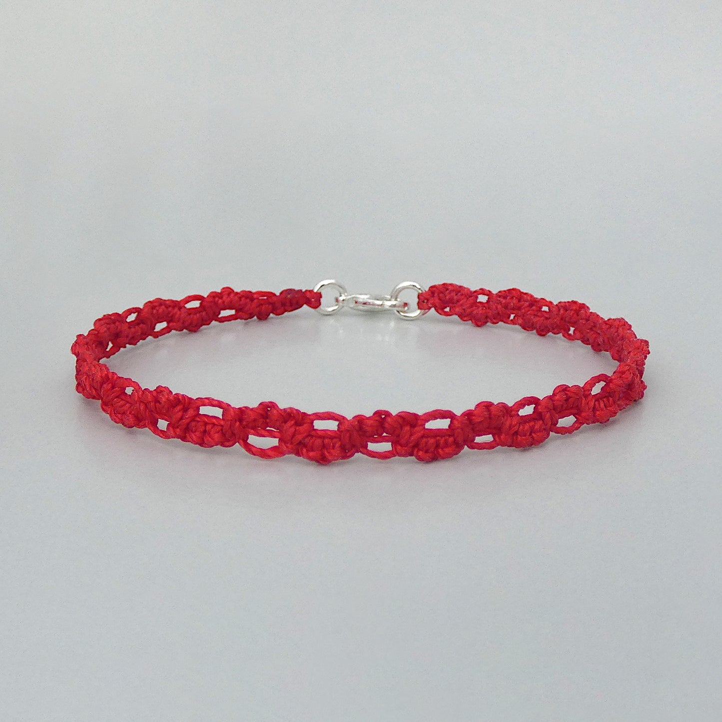 Red macramé bracelet tied with an intricate lace effect with silver plated clasp and optional 1” extender chain.