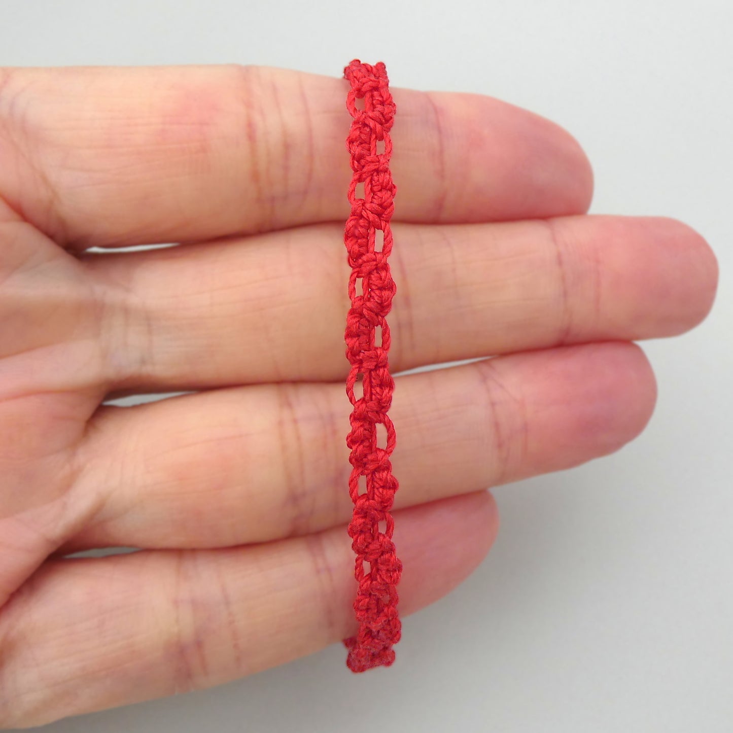 Red macramé bracelet tied with an intricate lace effect with silver plated clasp and optional 1” extender chain.