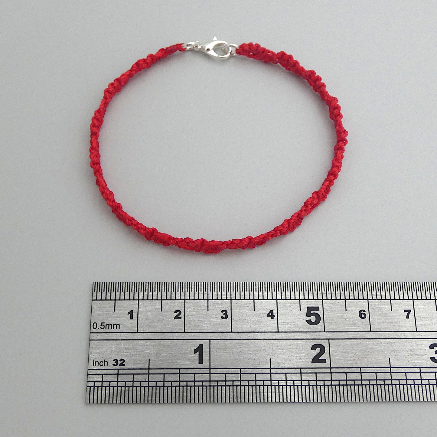 Red macramé bracelet tied with an intricate lace effect with silver plated clasp and optional 1” extender chain.