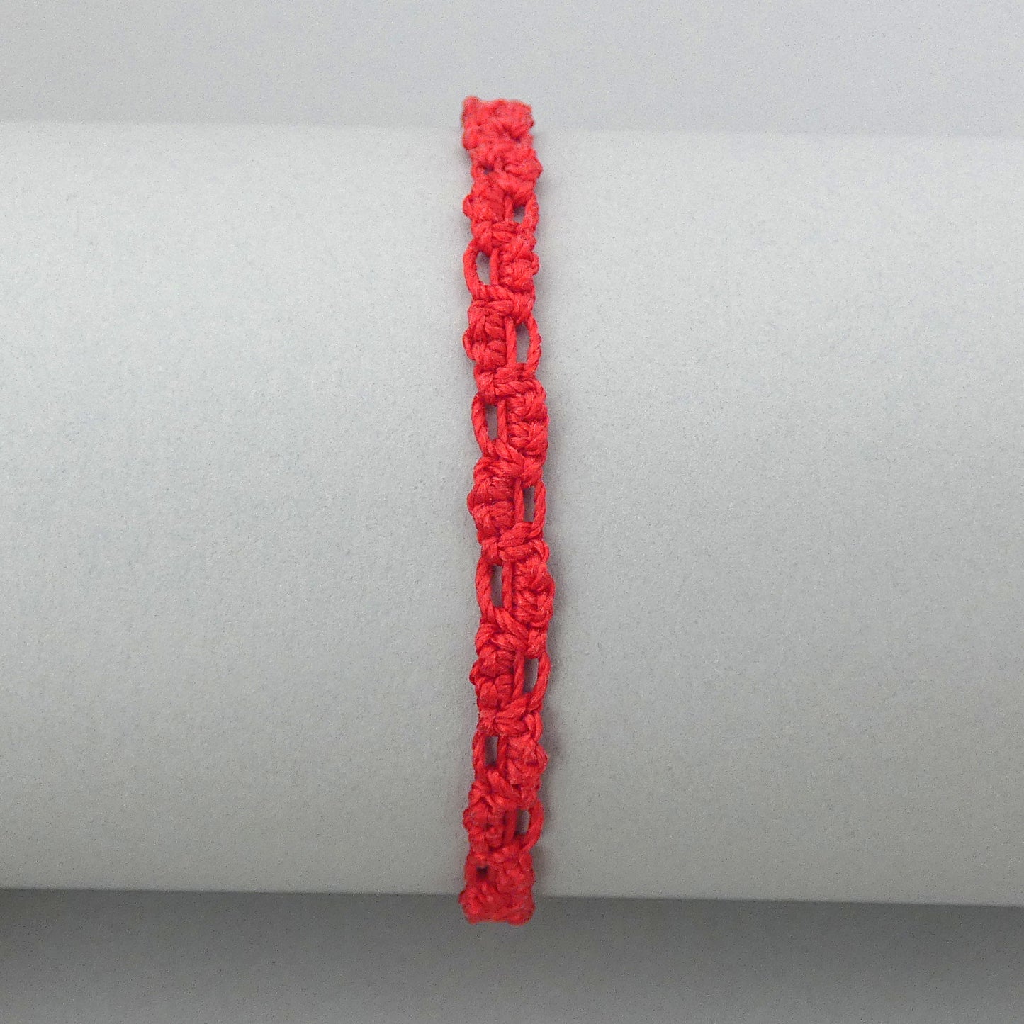 Red macramé bracelet tied with an intricate lace effect with silver plated clasp and optional 1” extender chain.