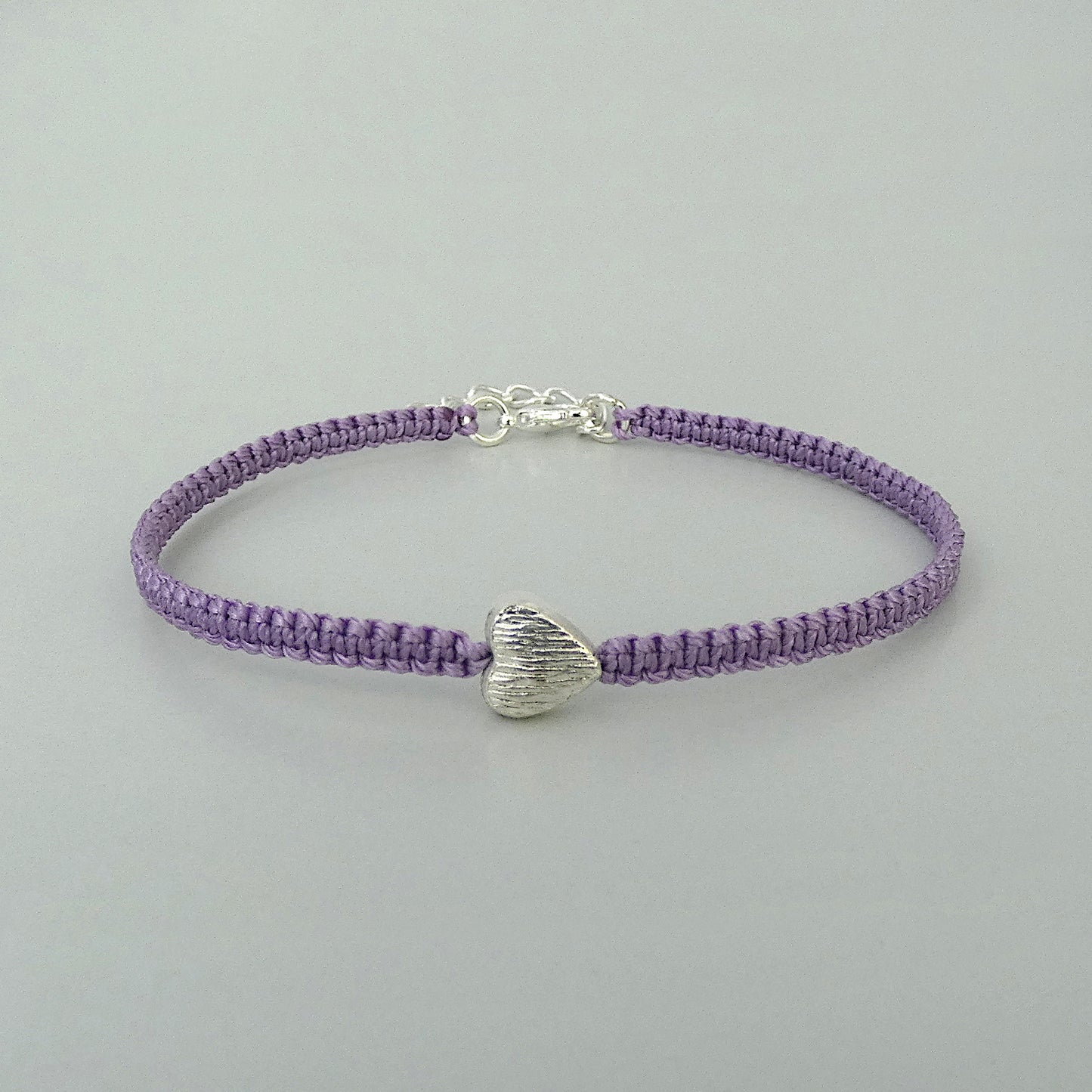 Orchid purple seven inch macramé bracelet with silver plated textured heart charm, lobster clasp and one inch extender chain.