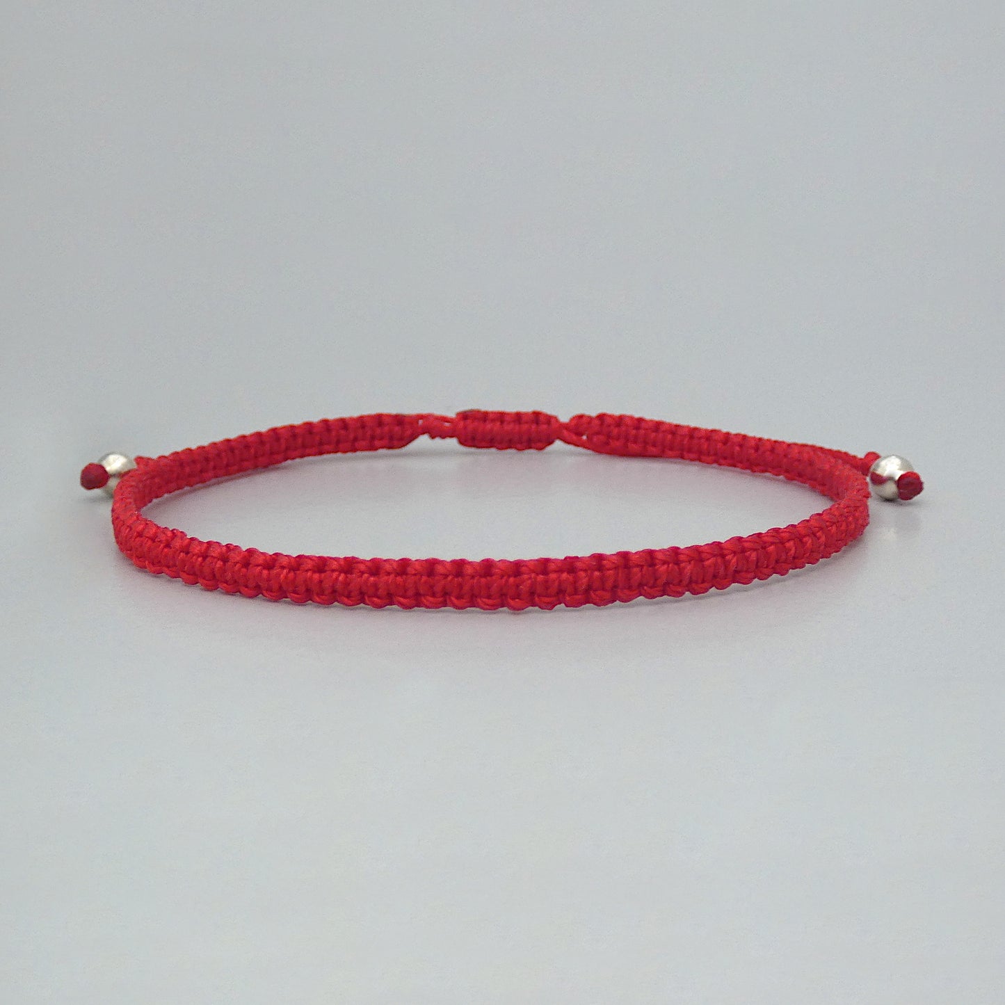 7” adjustable bright red coloured macramé bracelet for adults with silver plated bead ends.