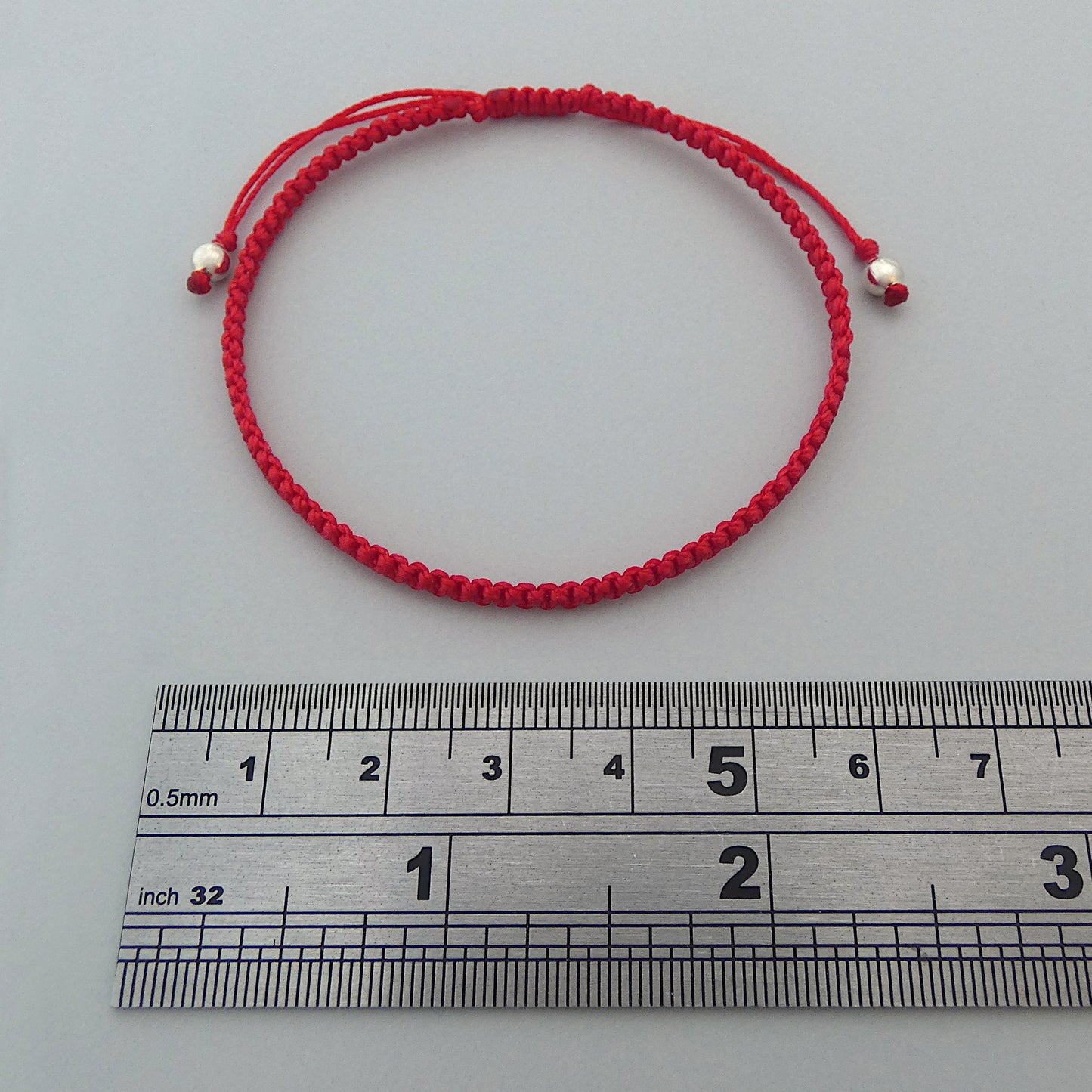 7” adjustable bright red coloured macramé bracelet for adults with silver plated bead ends.