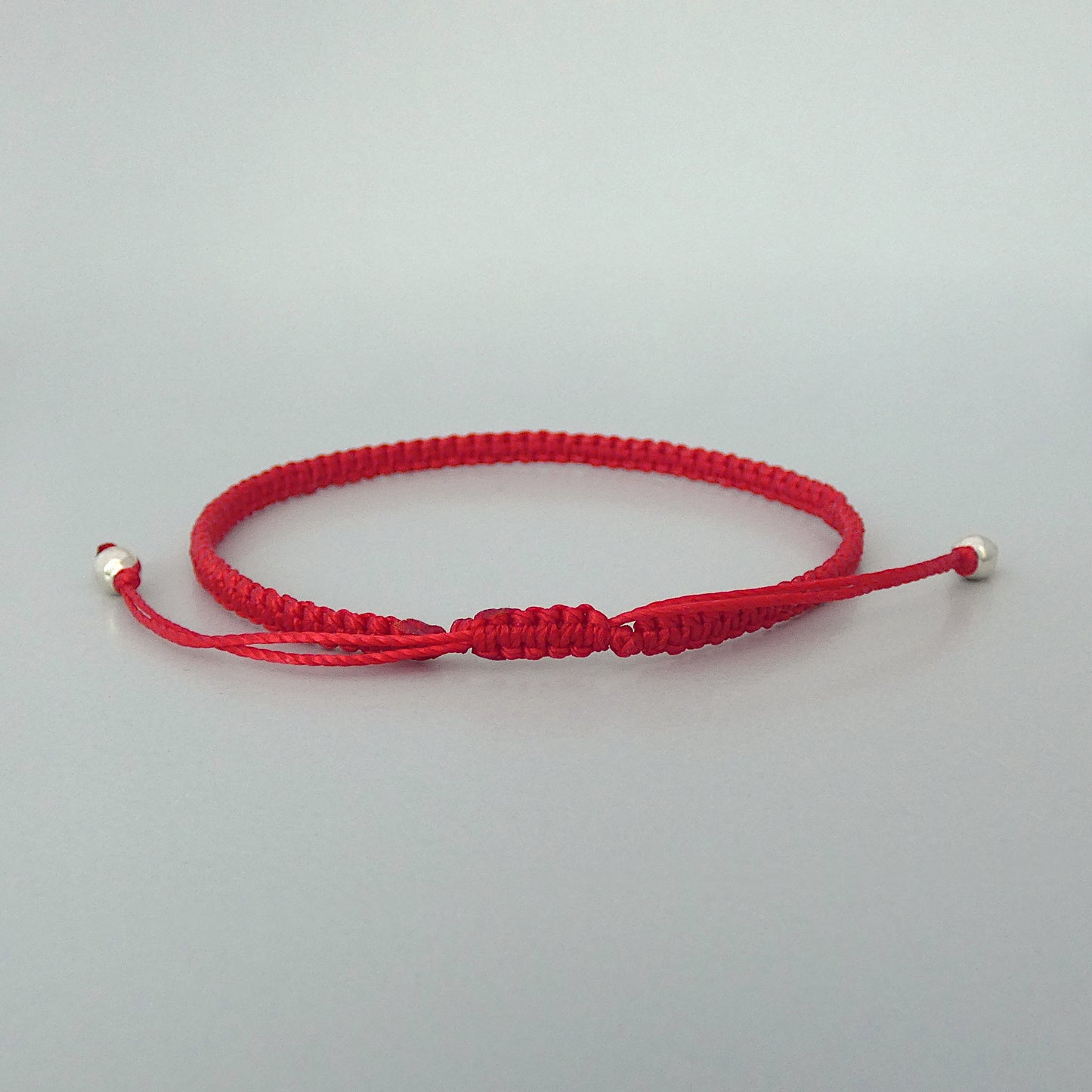 7” adjustable bright red coloured macramé bracelet for adults with silver plated bead ends.