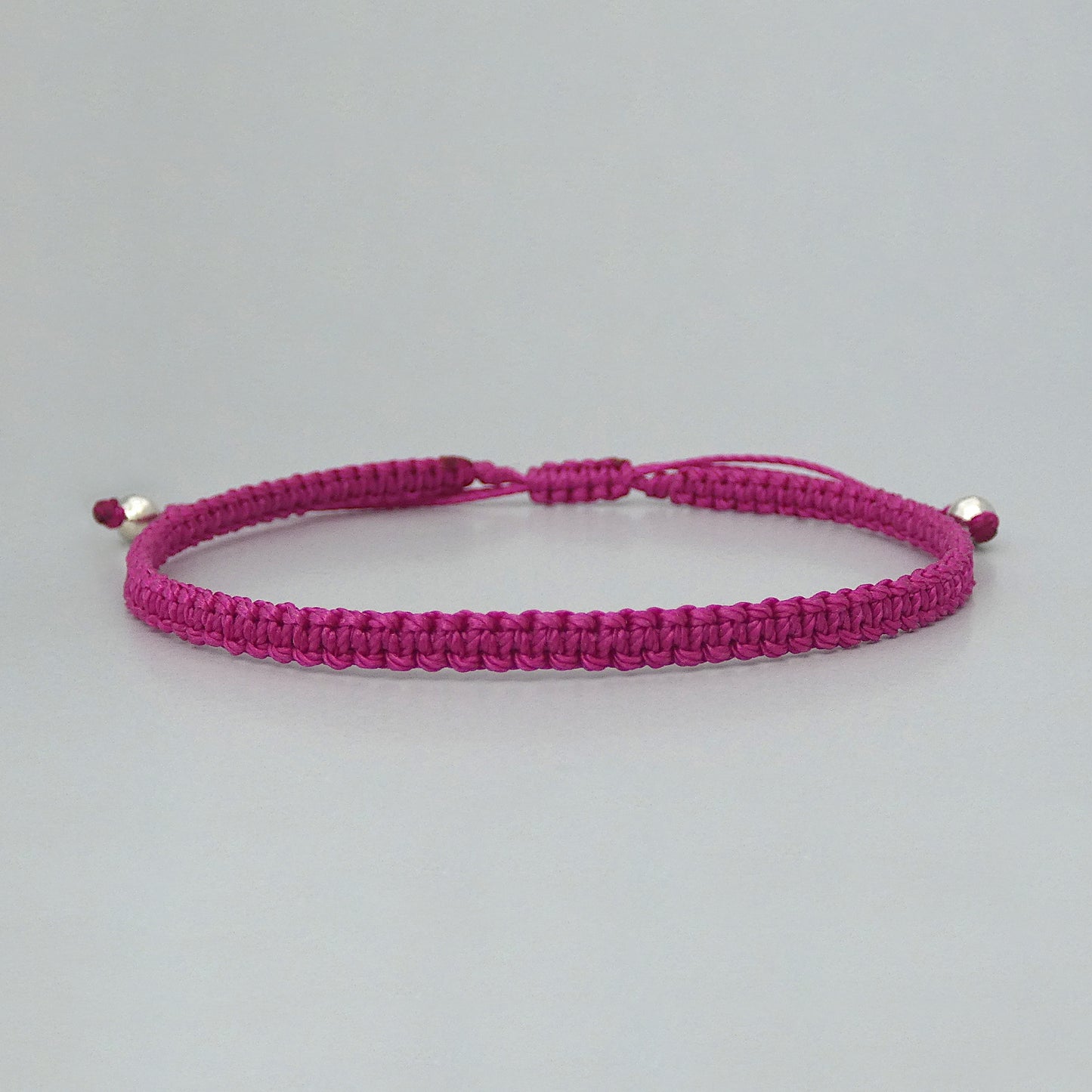 7” adjustable magenta macramé bracelet for adults with silver plated bead ends.
