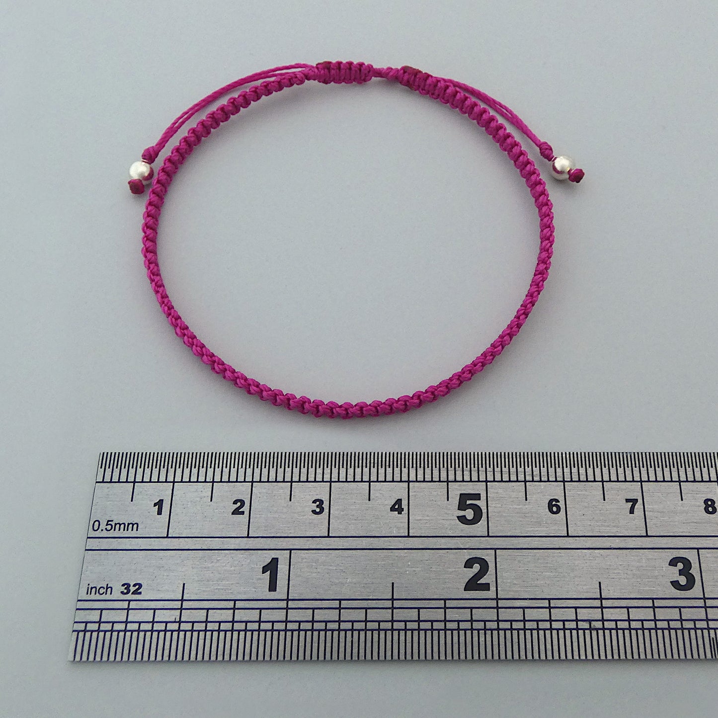 7” adjustable magenta macramé bracelet for adults with silver plated bead ends.