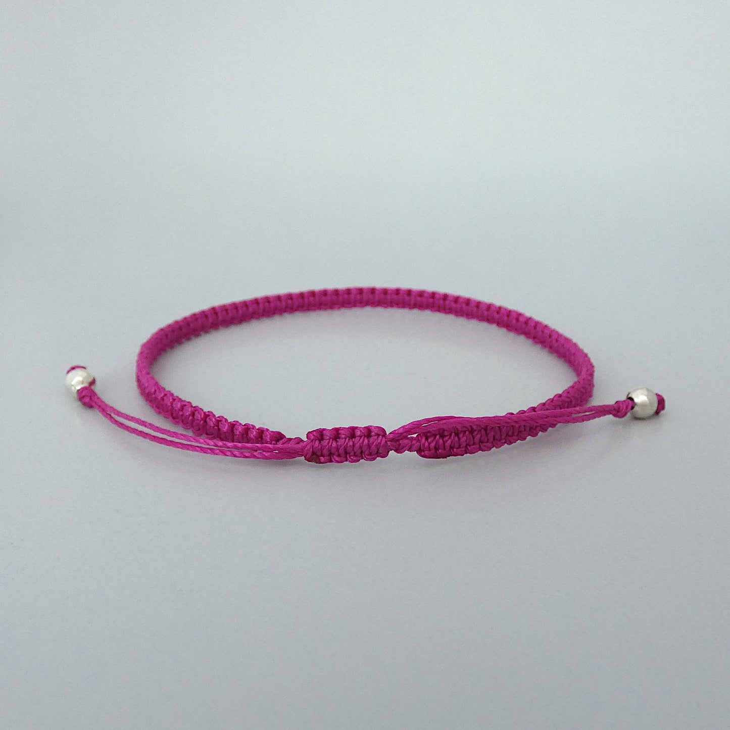 7” adjustable magenta macramé bracelet for adults with silver plated bead ends.