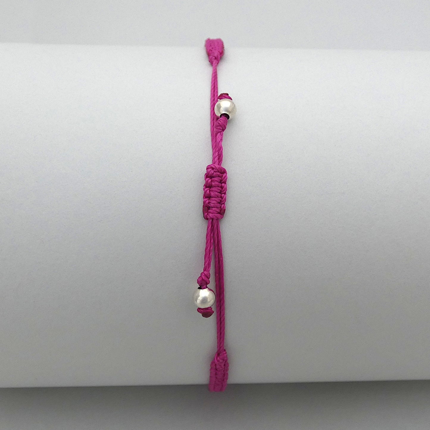 7” adjustable magenta macramé bracelet for adults with silver plated bead ends.