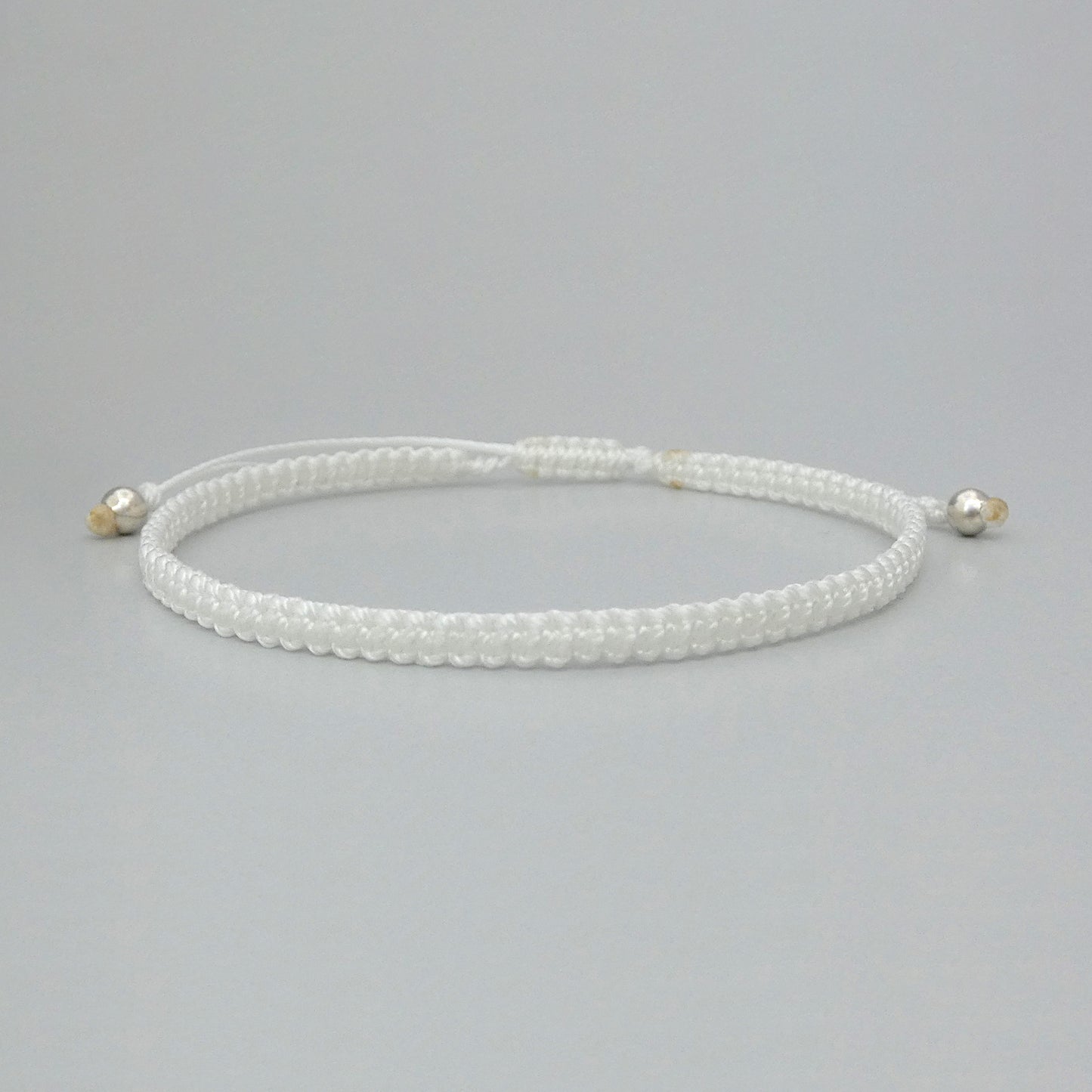 7” adjustable white macramé bracelet for adults with silver plated bead ends.