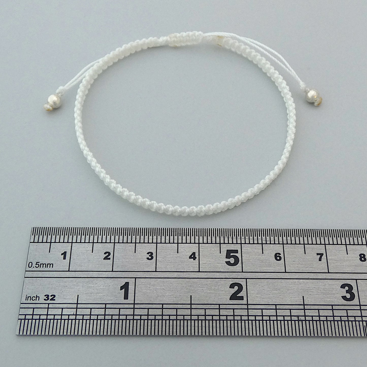 7” adjustable white macramé bracelet for adults with silver plated bead ends.