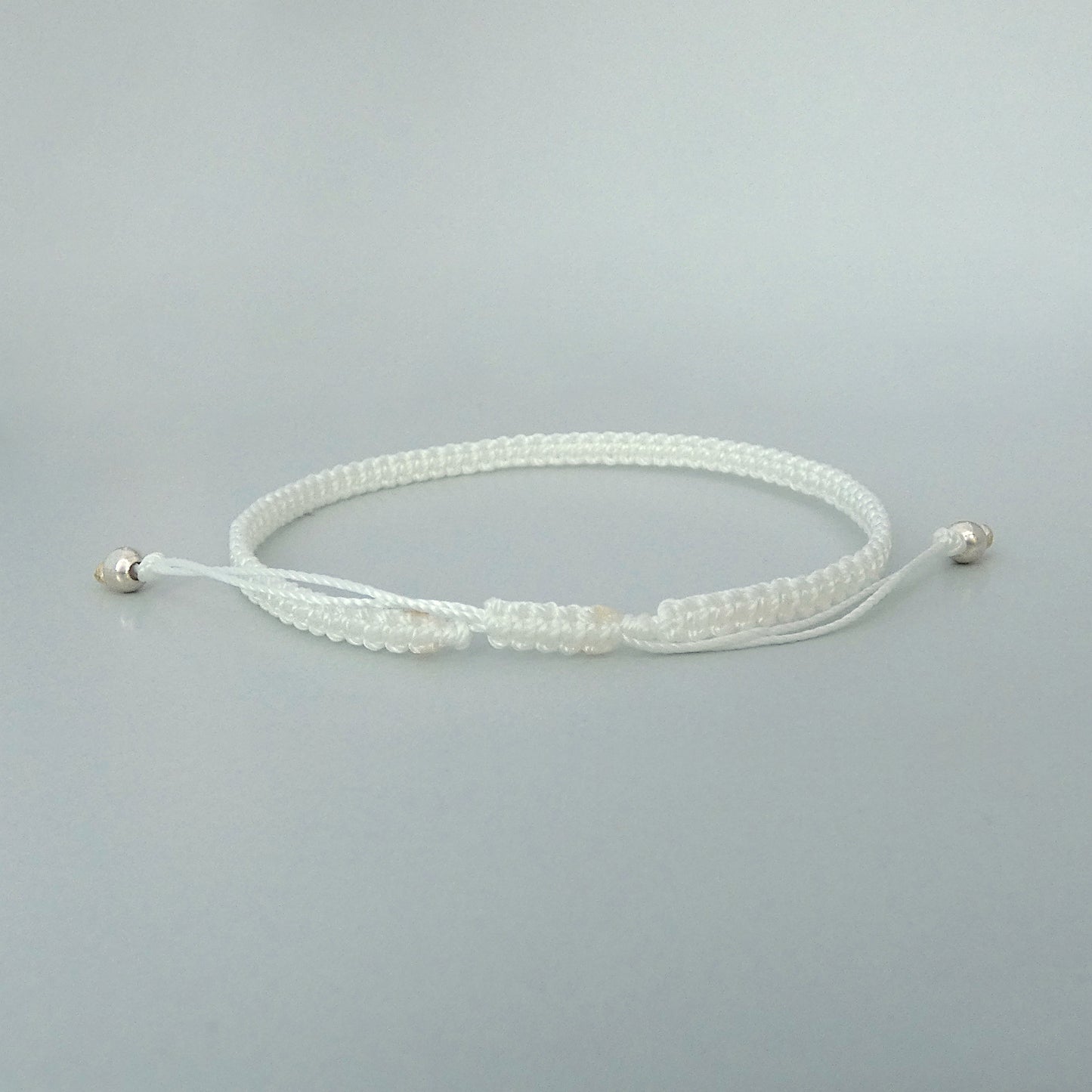 7” adjustable white macramé bracelet for adults with silver plated bead ends.