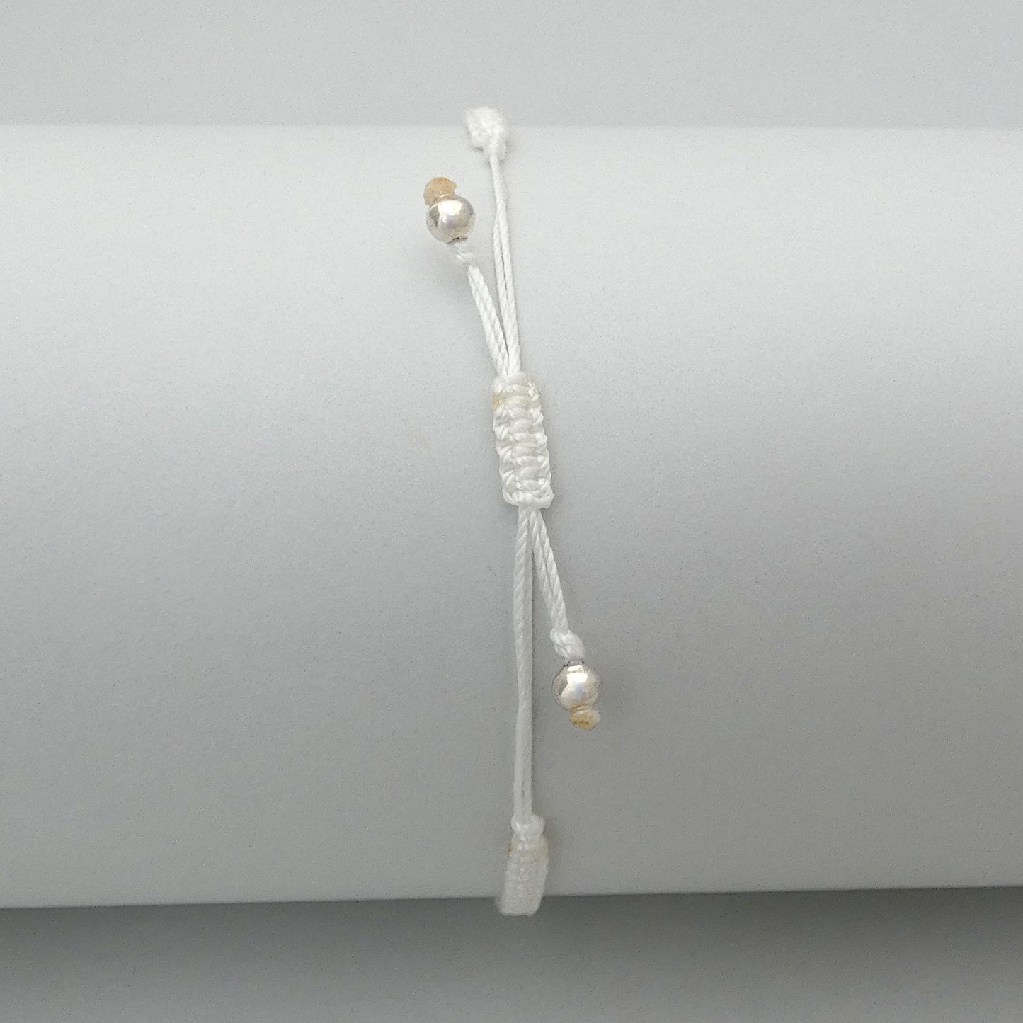7” adjustable white macramé bracelet for adults with silver plated bead ends.