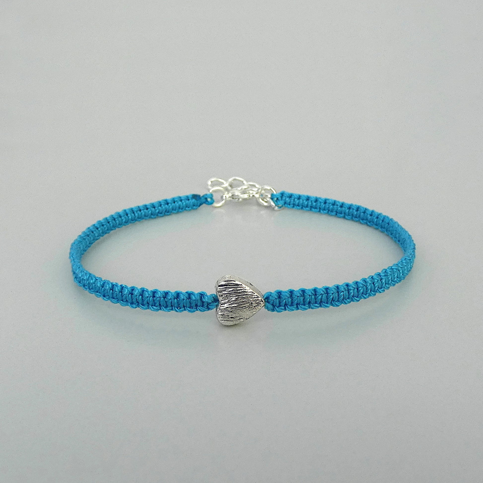 Blue seven inch macramé bracelet with silver plated textured heart charm, lobster clasp and one inch extender chain.