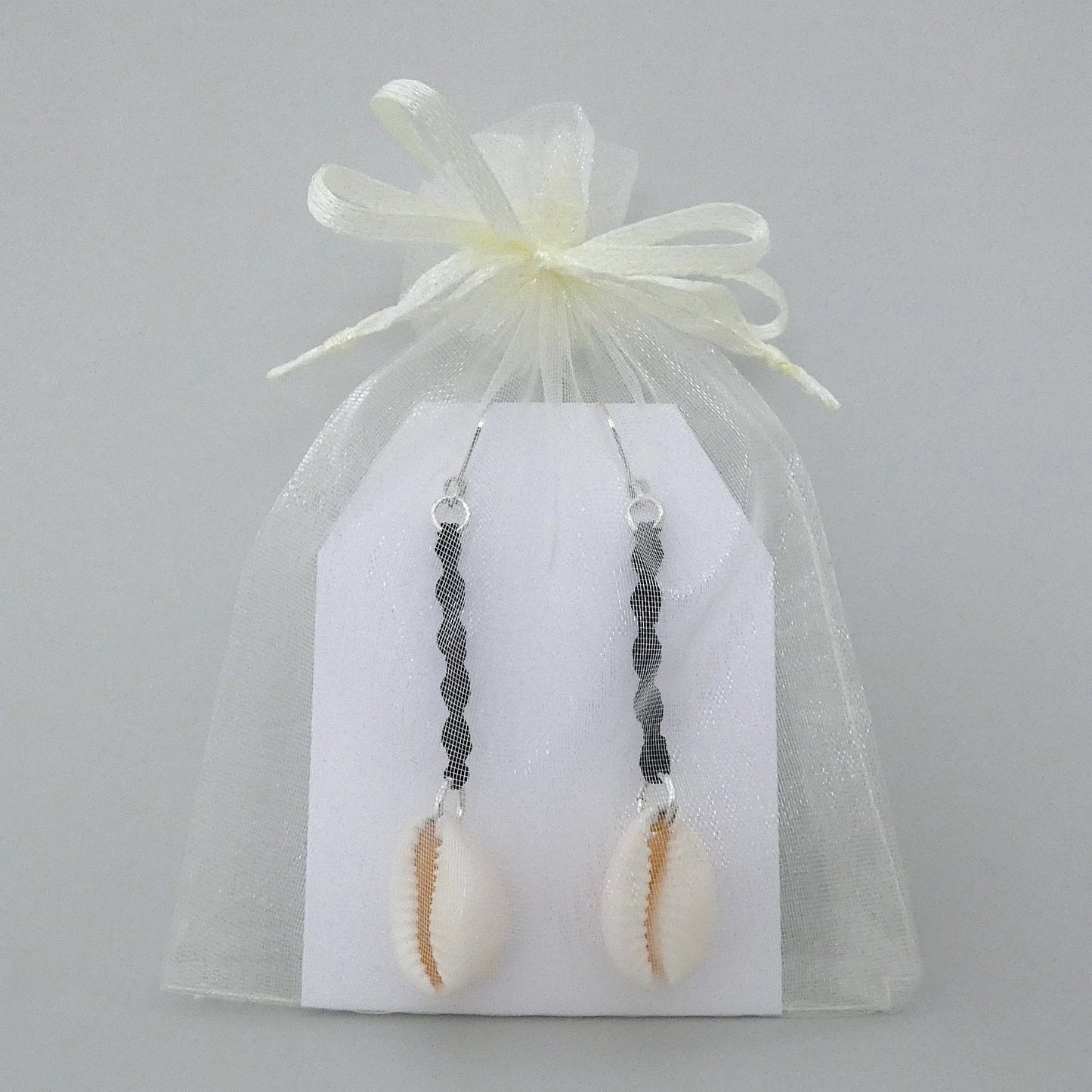 Silver plated leverback earrings with cowrie shells and black macramé twist detail.