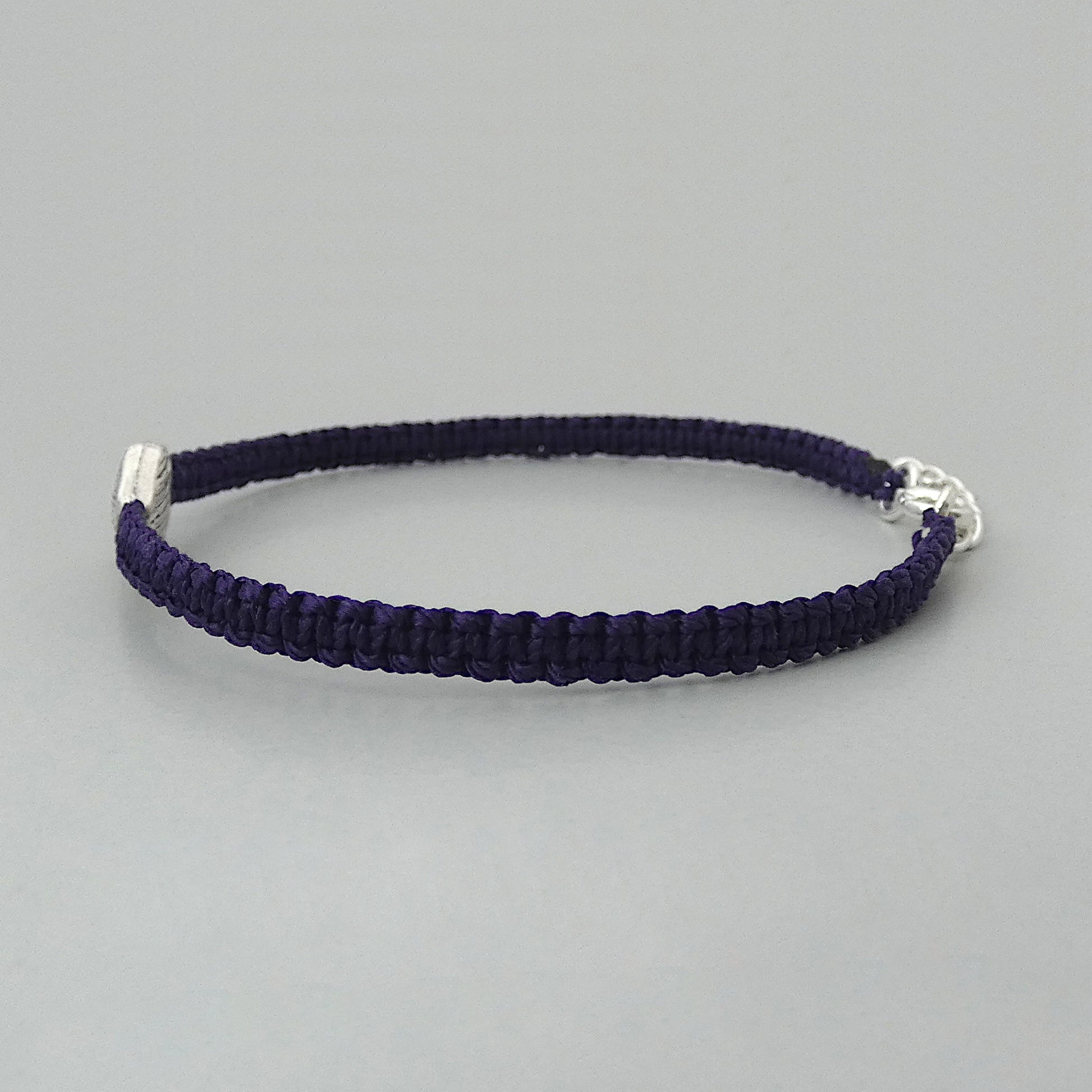 Side view of the knots on a dark purple seven inch macramé bracelet with silver plated textured heart charm, lobster clasp and one inch extender chain.