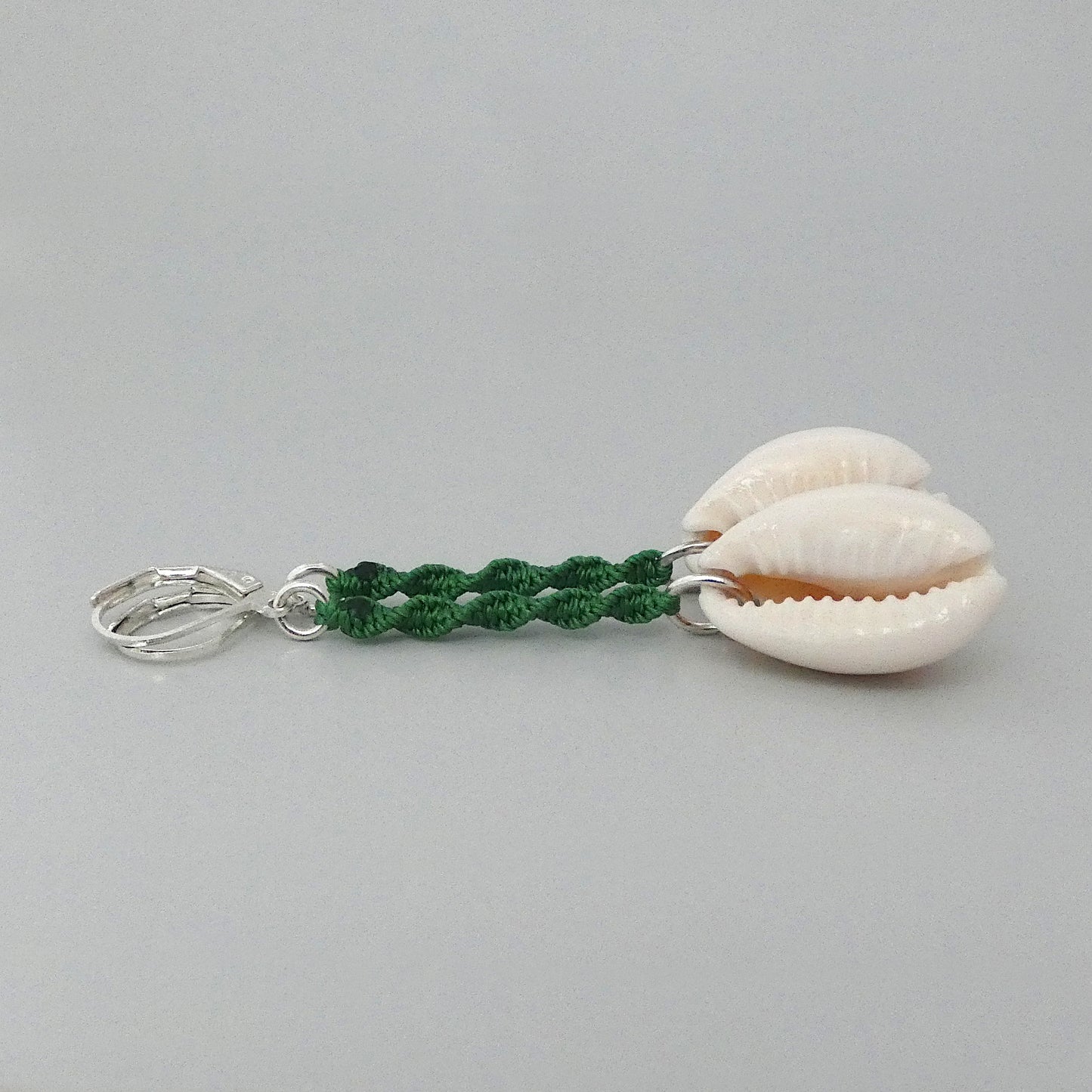 Silver plated leverback earrings with cowrie shells and green macramé twist detail.
