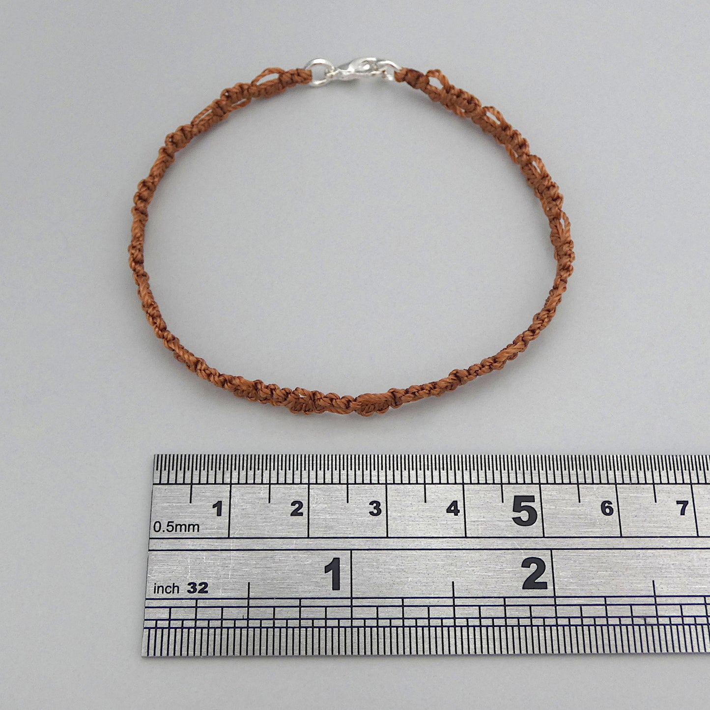Copper coloured macramé bracelet tied with an intricate lace effect with silver plated clasp and optional 1” extender chain.